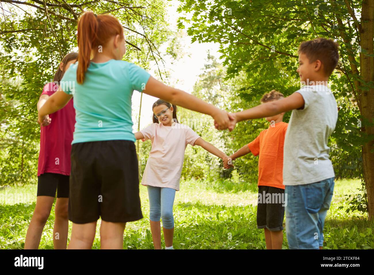 Friends holding hands while playing ring-around-the-rosy at park Stock Photo