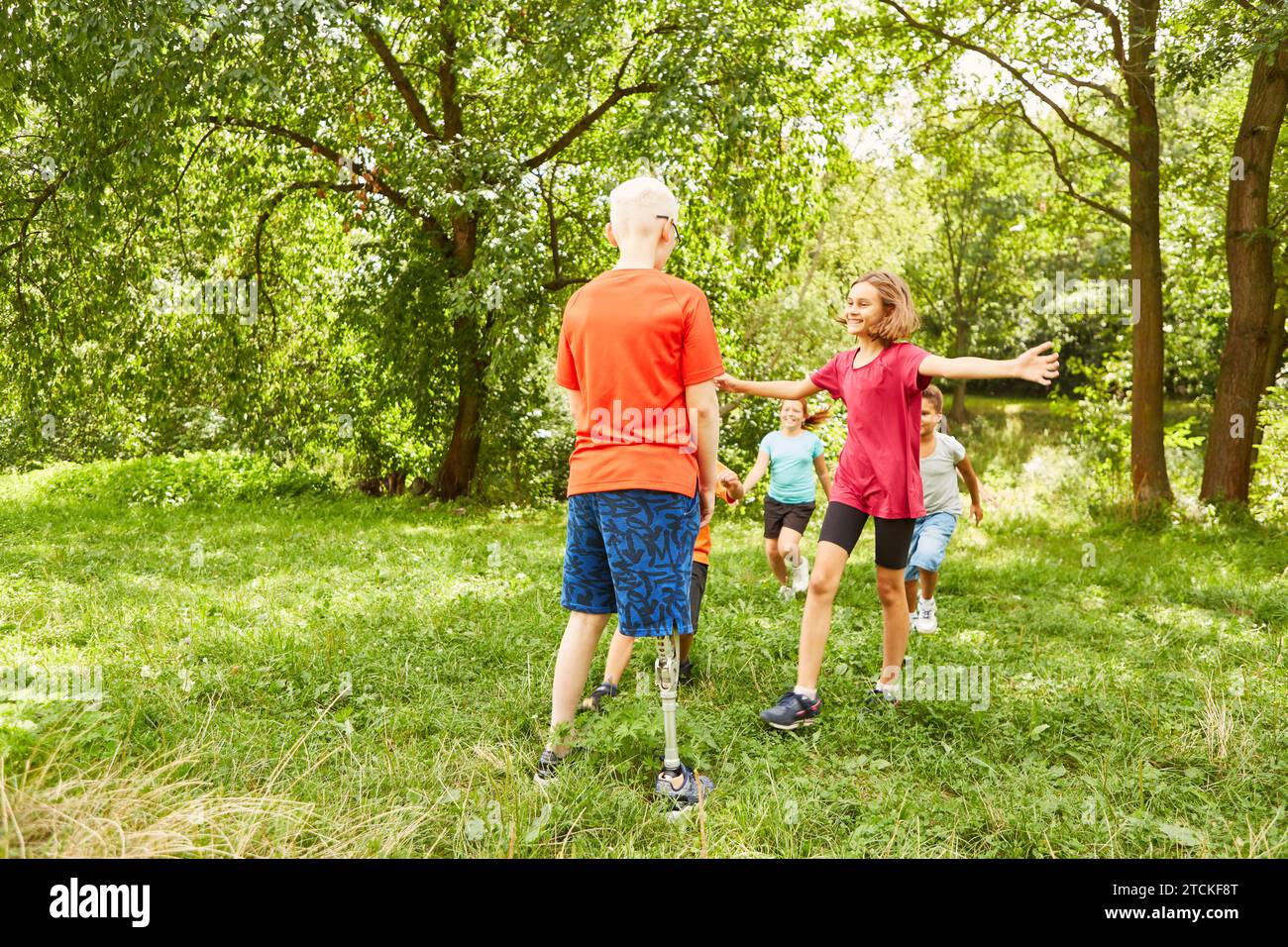 Happy friends walking towards disabled boy standing at park Stock Photo
