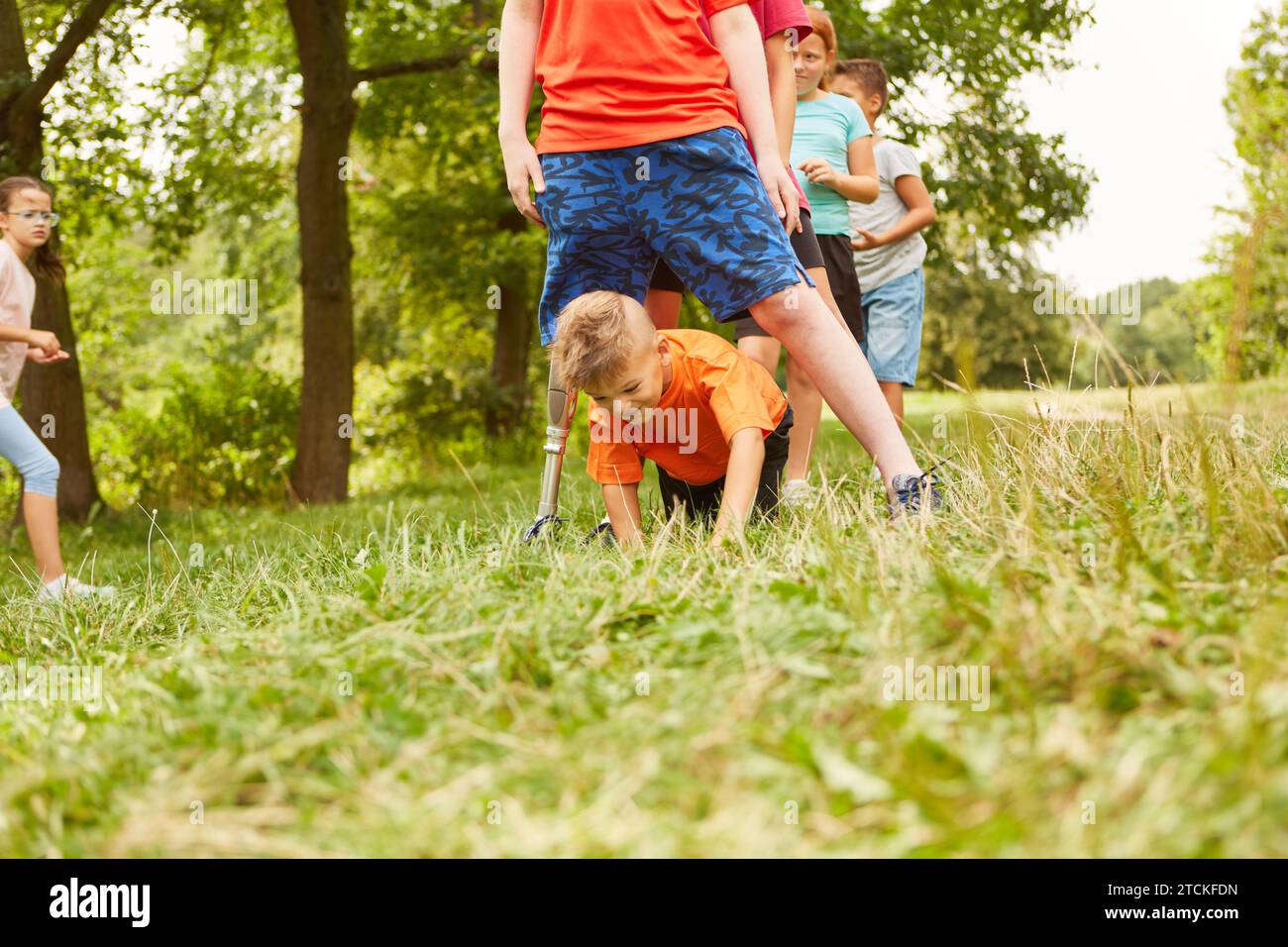 Happy boy crawling below disabled friend while playing together at park Stock Photo