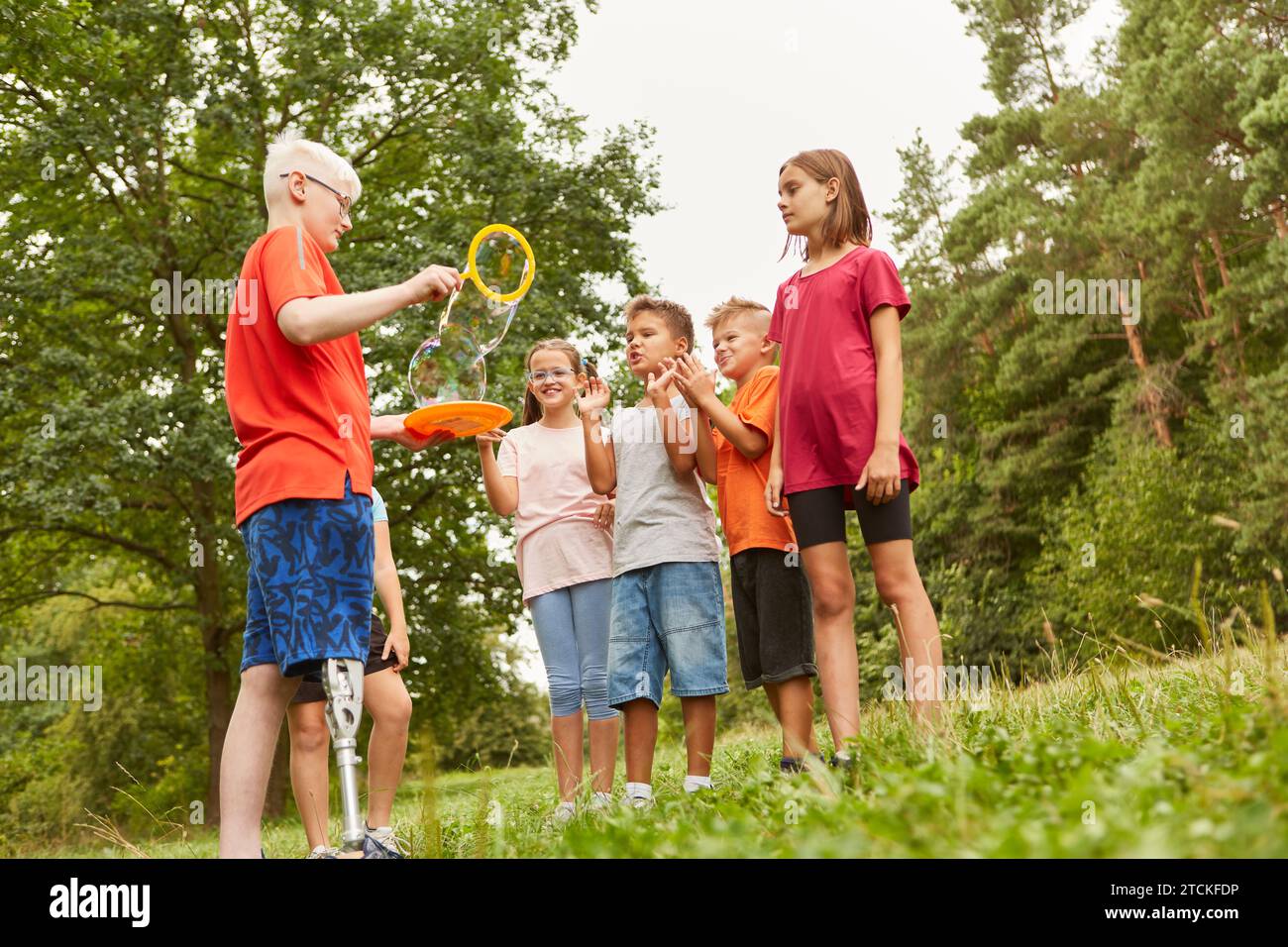 Friends having fun with disabled boy holding bubble wand at park Stock Photo