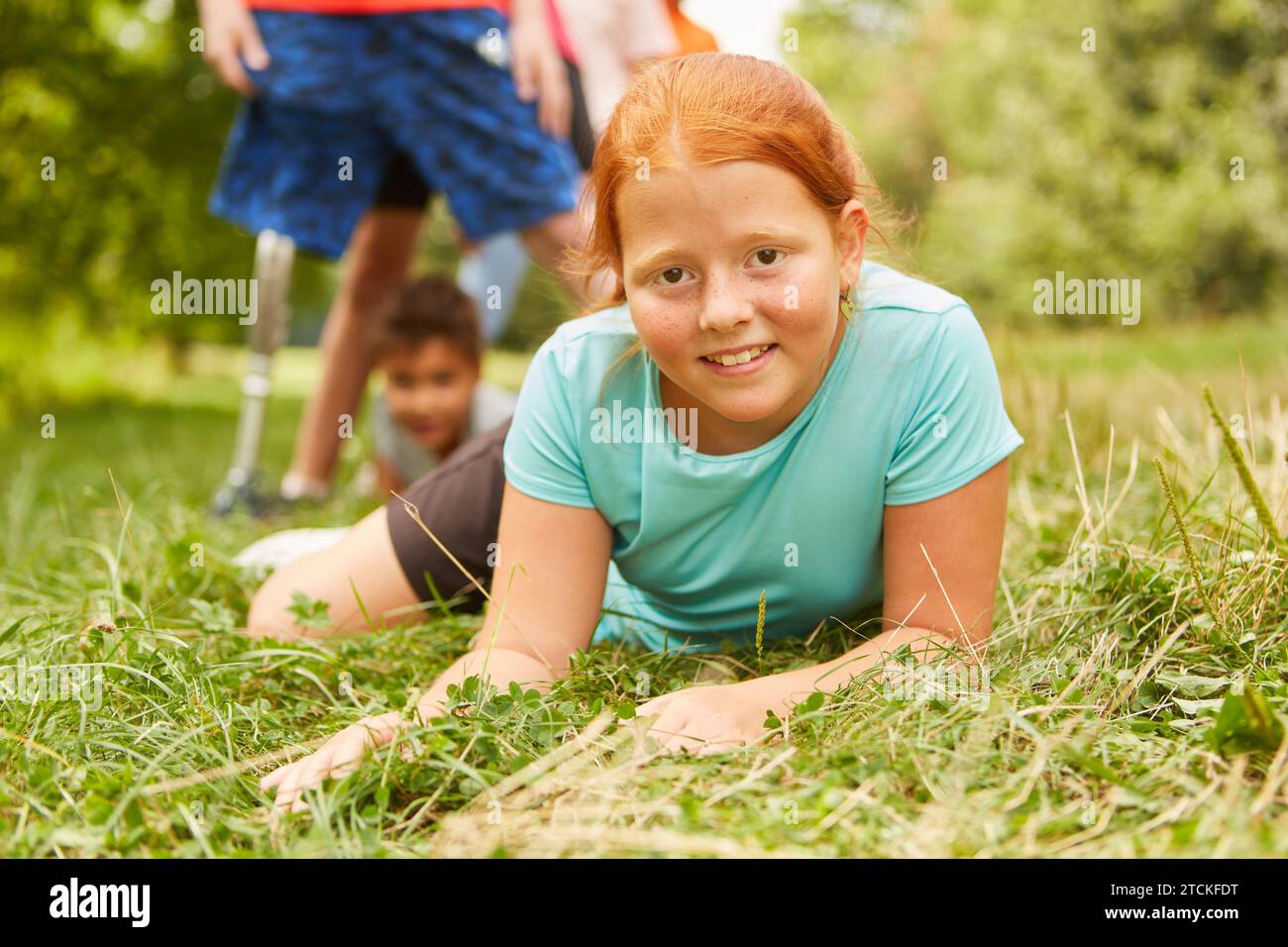 Portrait of smiling redhead girl lying down on grass at park Stock Photo