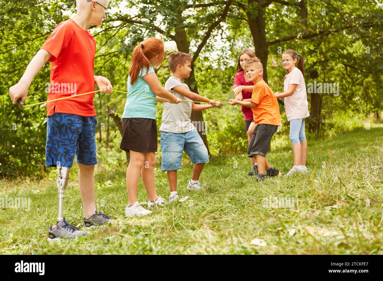 Kids having fun while playing tug of war on grass at park Stock Photo