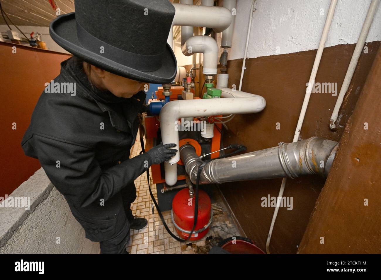 Munich, Germany. 13th Dec, 2023. Chimney sweep Diane Löbel inspects an oil heating system in the basement of a detached house. From January, only heating systems based on 65 percent renewable energy may be installed in new buildings in new development areas. In many cases, this is likely to be a heat pump. Credit: Felix Hörhager/dpa/Alamy Live News Stock Photo