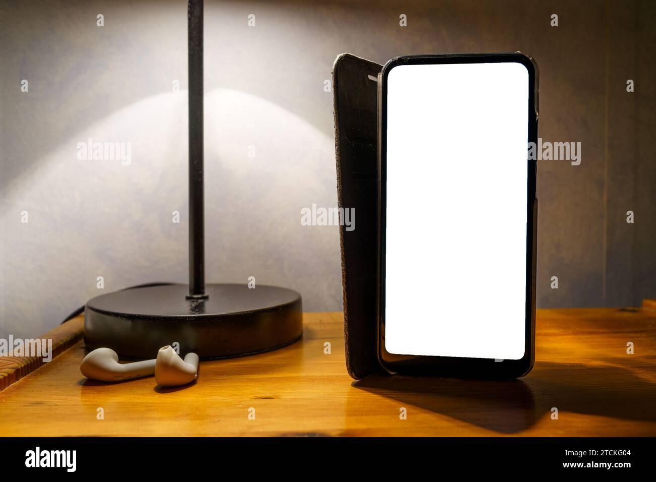 Smart phone with flip case and empty white screen on bedside table, clipping path Stock Photo