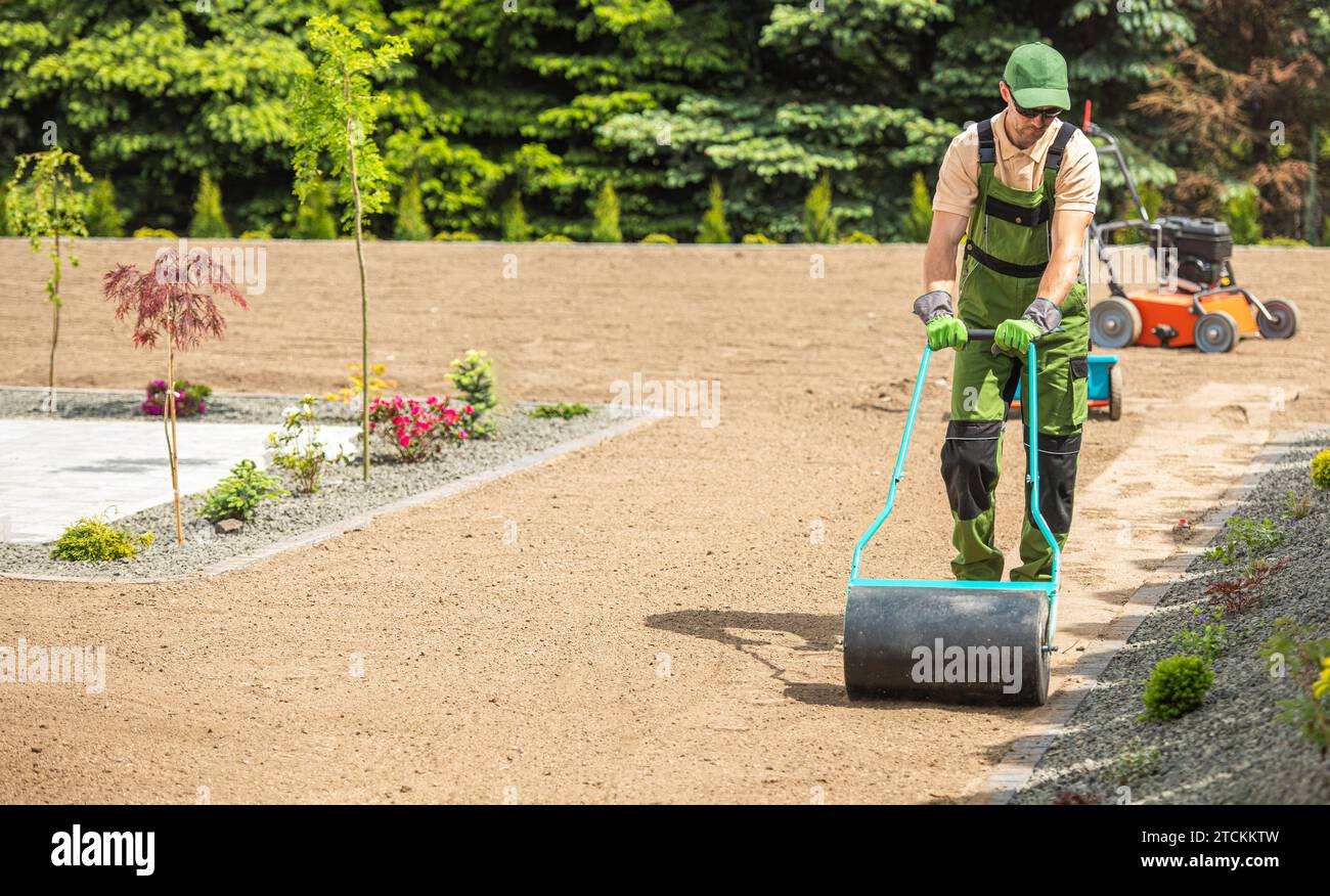 Professional Caucasian Landscaper Preparing Backyard Garden Soil For Grass Seeding Using