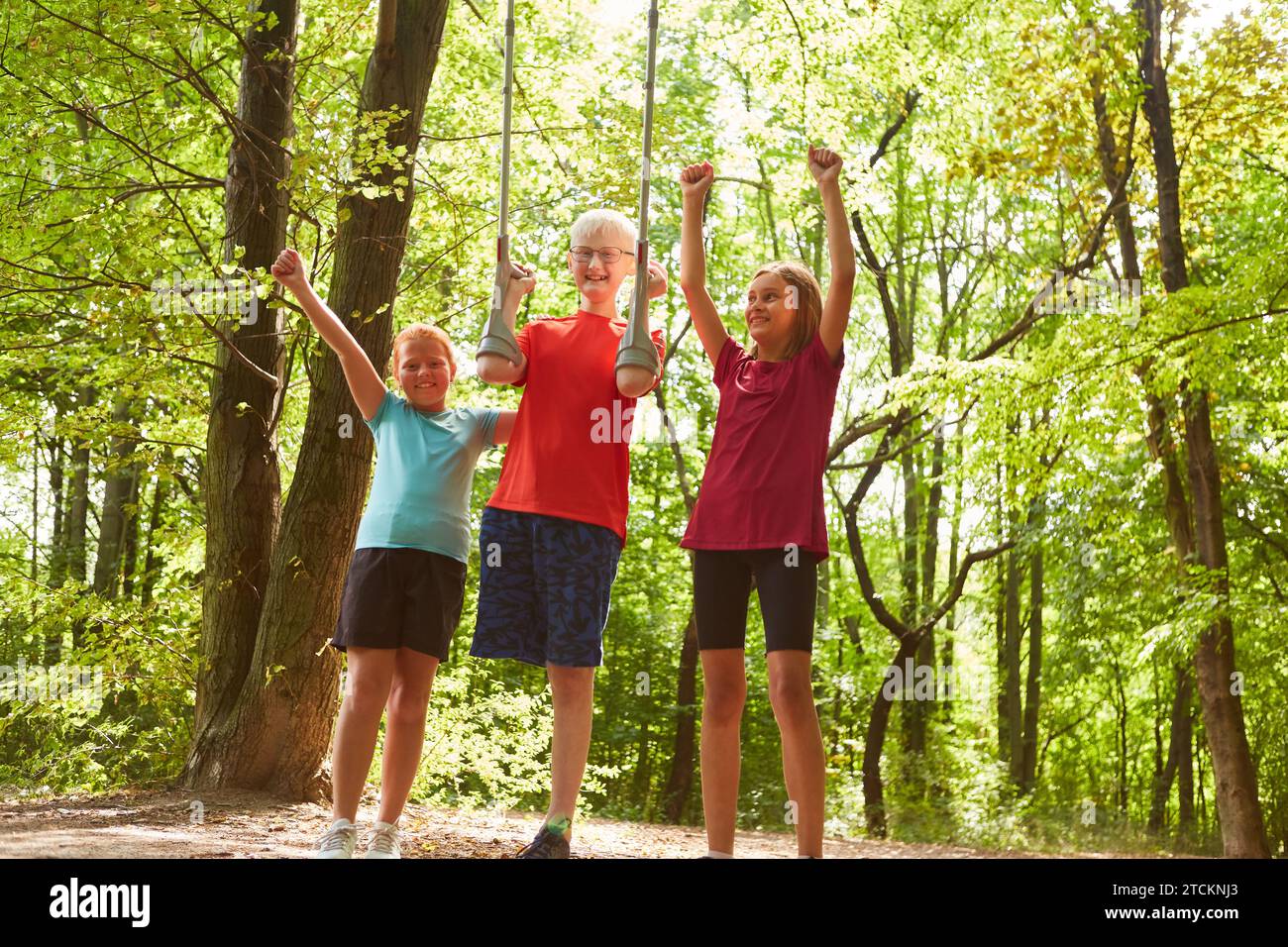 Happy female friends cheering with male disabled friend holding crutches while standing in forest Stock Photo