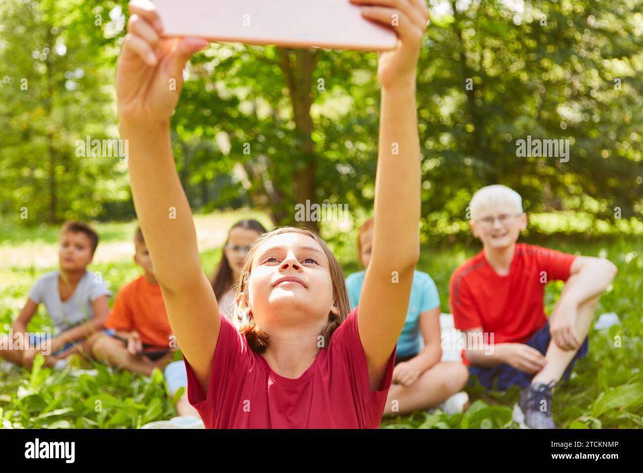 Girl taking selfie with friends through tablet PC at park Stock Photo
