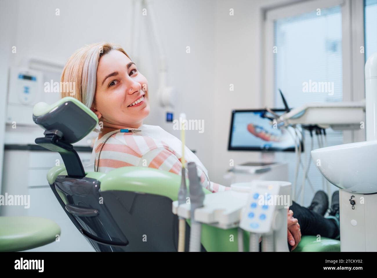 Portrait of young smiling woman sitting in stomatology clinic chair