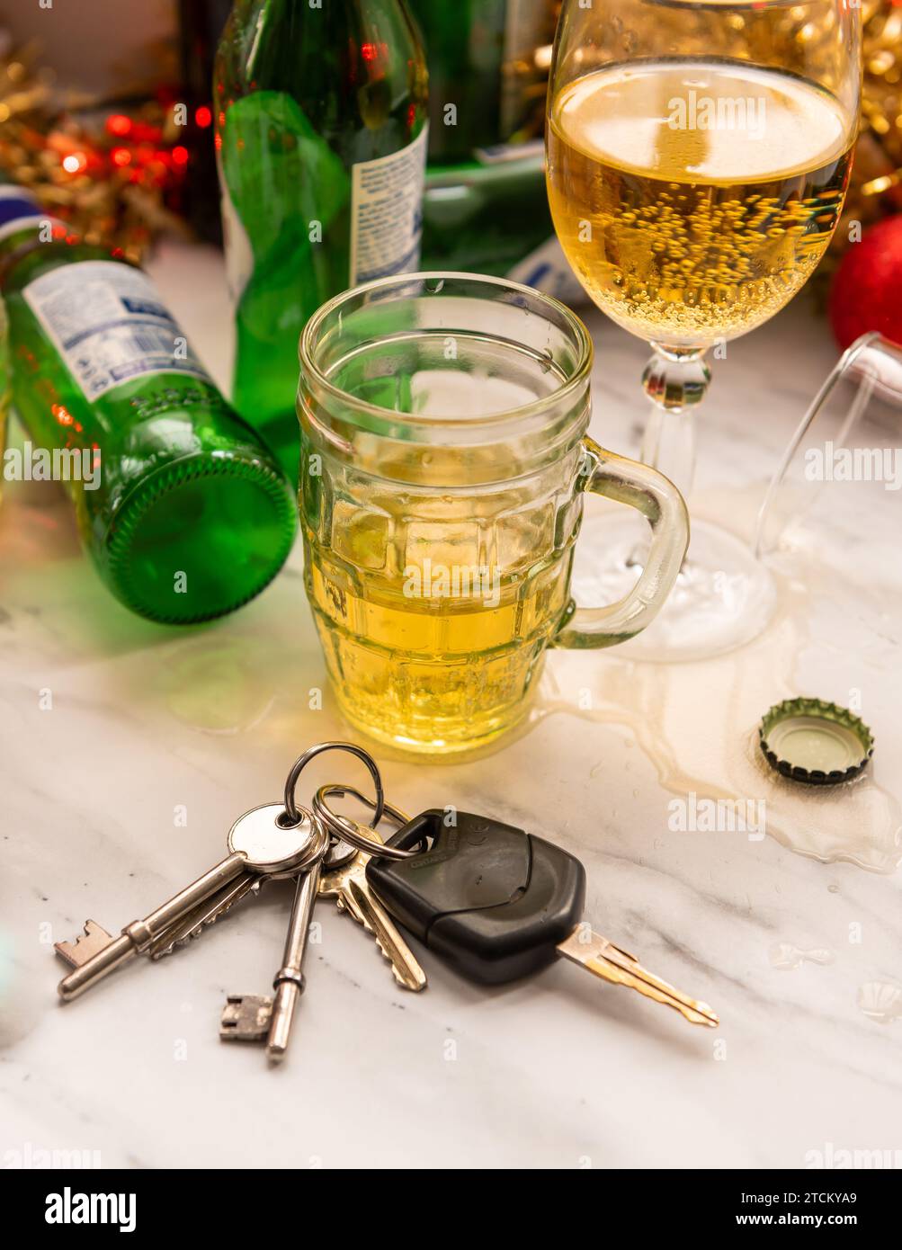 A Christmas, festive drink driving concept with a set of car keys on a table full of alcoholic drinks and decorations. Stock Photo