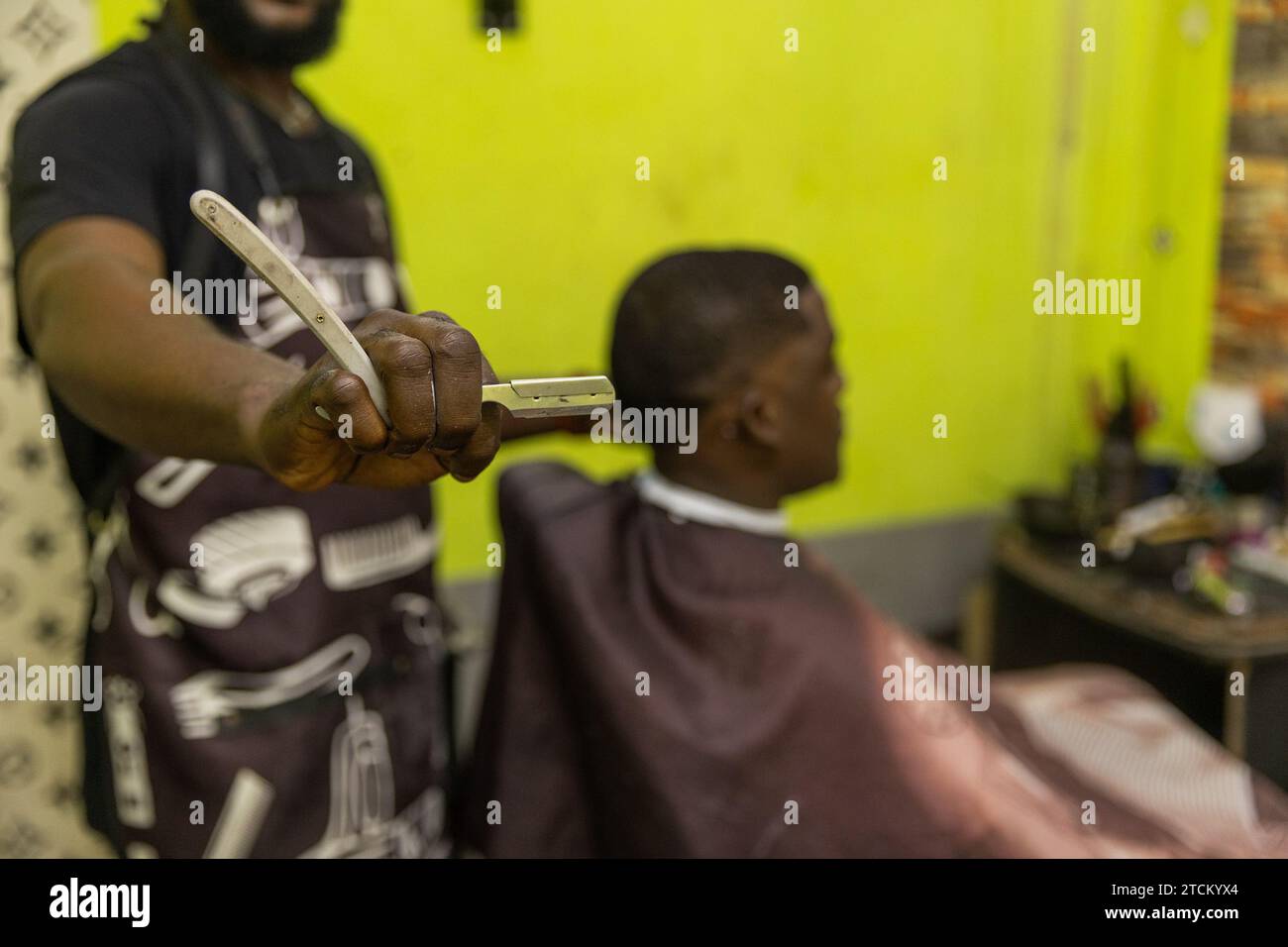 Close-up of a straight razor held by a barber during a haircut to his client. Stock Photo