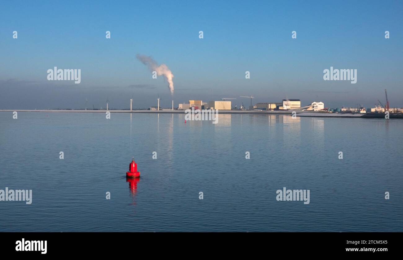 Industrial area on the coast, seen from the sea. In the foreground a red buoy. Stock Photo