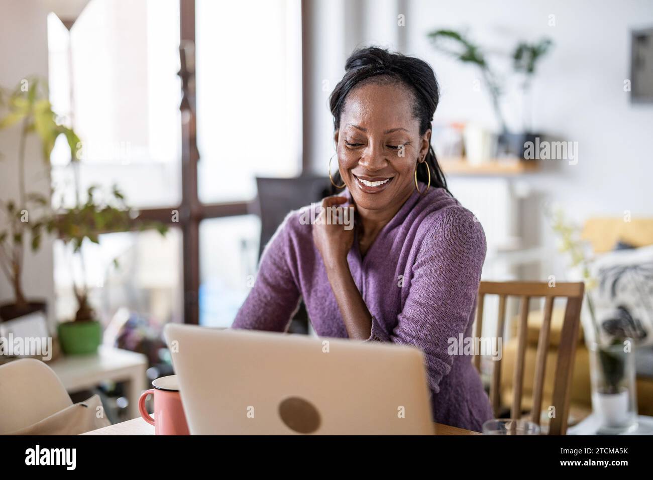 Smiling woman working on laptop at home Stock Photo