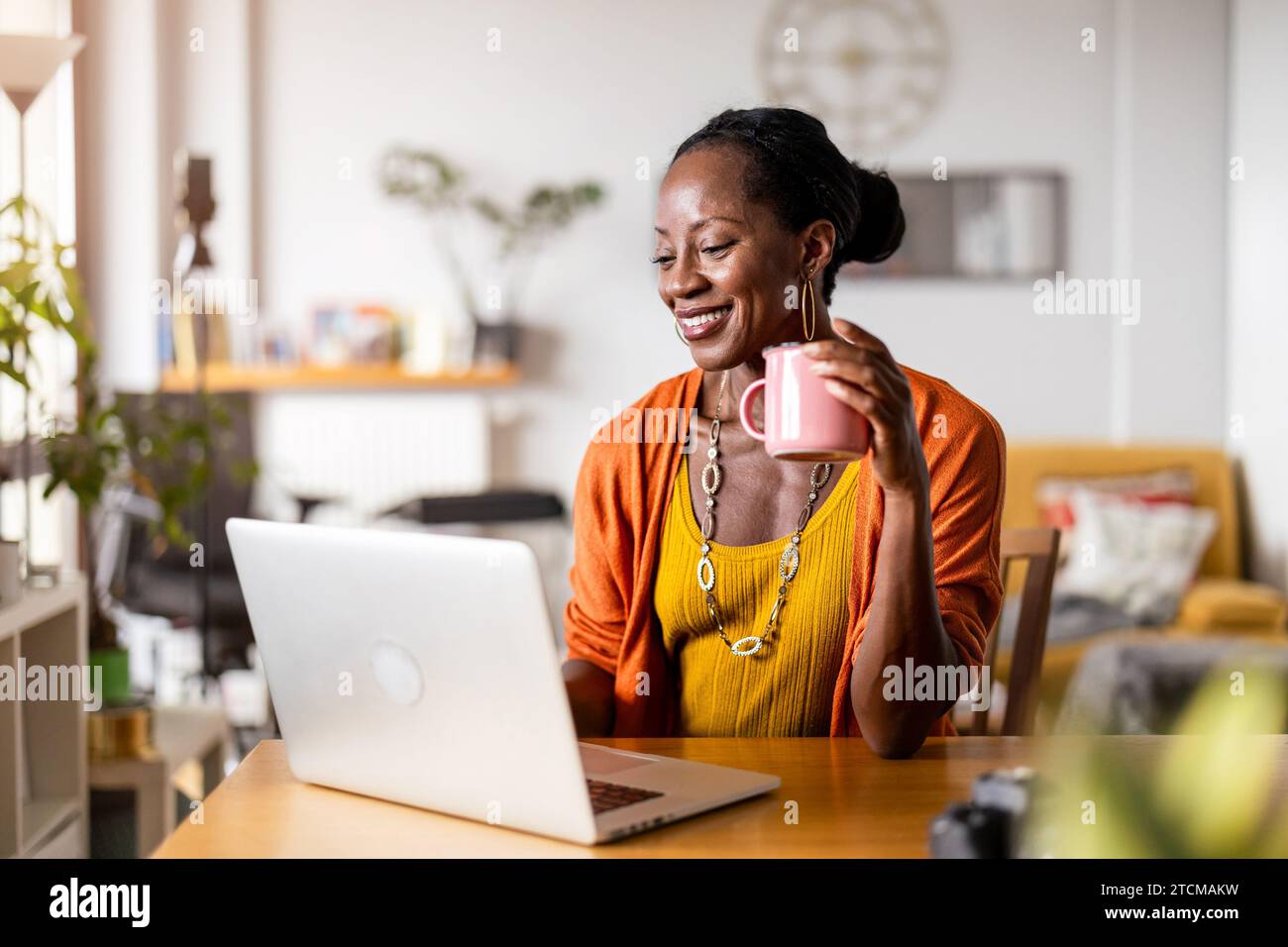 Smiling woman working on laptop at home Stock Photo