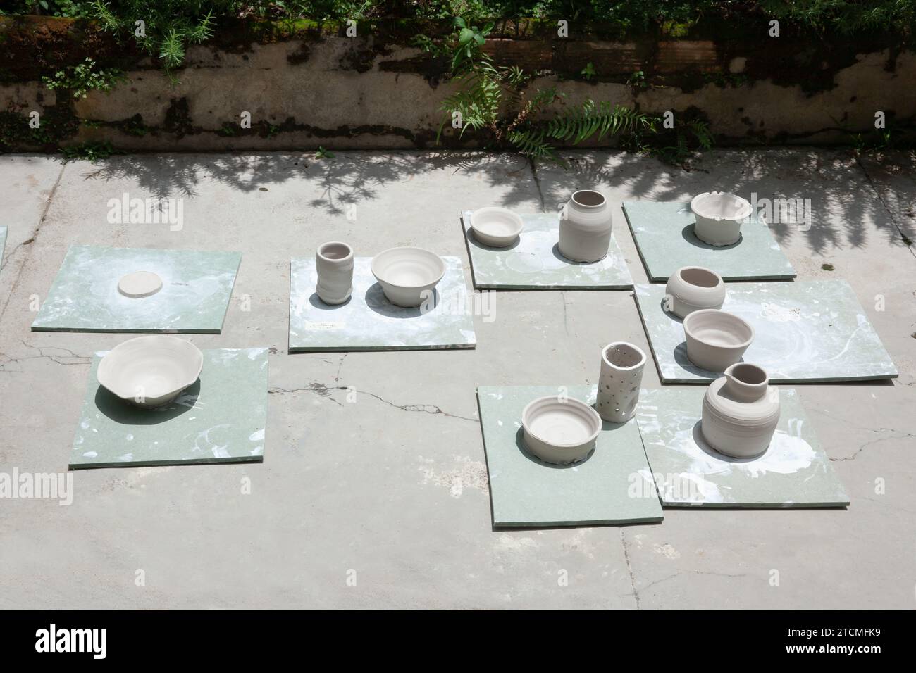 A group of white pottery crafts are drying in the sunny garden Stock Photo
