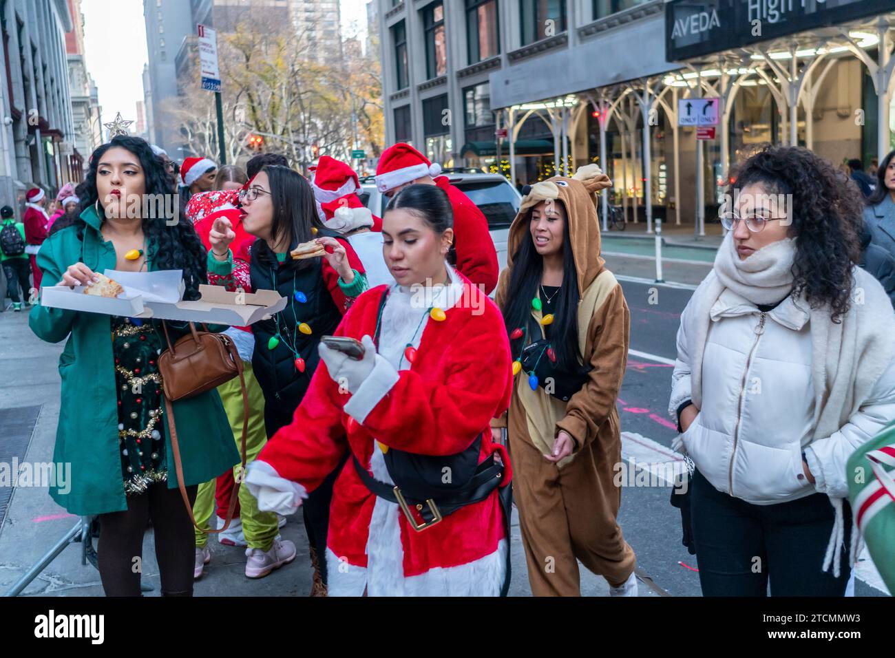 Hundreds of Santas, accompanied by their helpers and some naughty elves, wait on line to enter The Smith Bar in the NoMad neighborhood in Manhattan in New York during the annual bar crawl, SantaCon on Saturday, December 19, 2023.  SantaCon, primarily a bar crawl in Santa and other Christmas related costumes, attracts masqueraders going from bar to bar.  (© Richard B. Levine) Stock Photo
