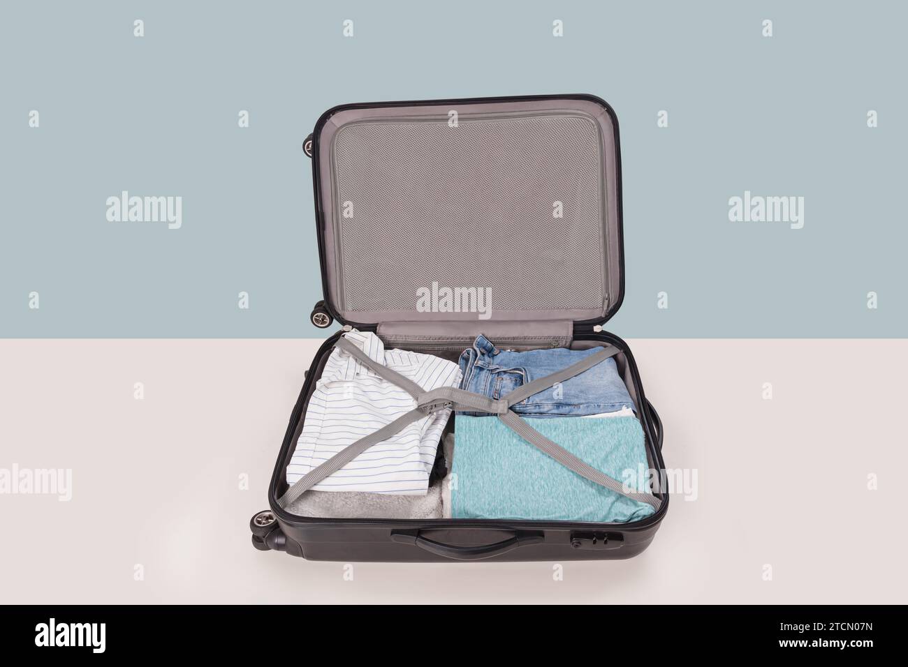 Open suitcase packed for trip isolated on light blue background Stock Photo