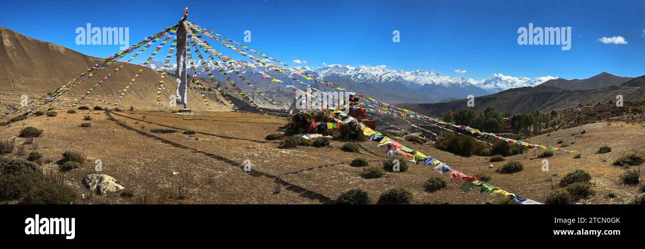 Prayer flags above Lo Gekar Monastery in Ghar village, the oldest Buddhist gompa in Nepal, built by Guru Rimpoche in the 8th century - Mustang Distric Stock Photo