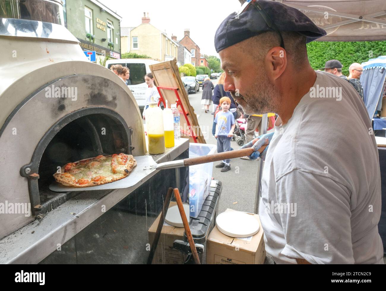 An outside stall in the Nether Edge street market. A pizza chef takes a