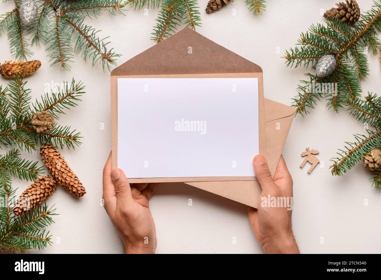 Man holding envelopes with blank paper, fir branches and pine cones on ...