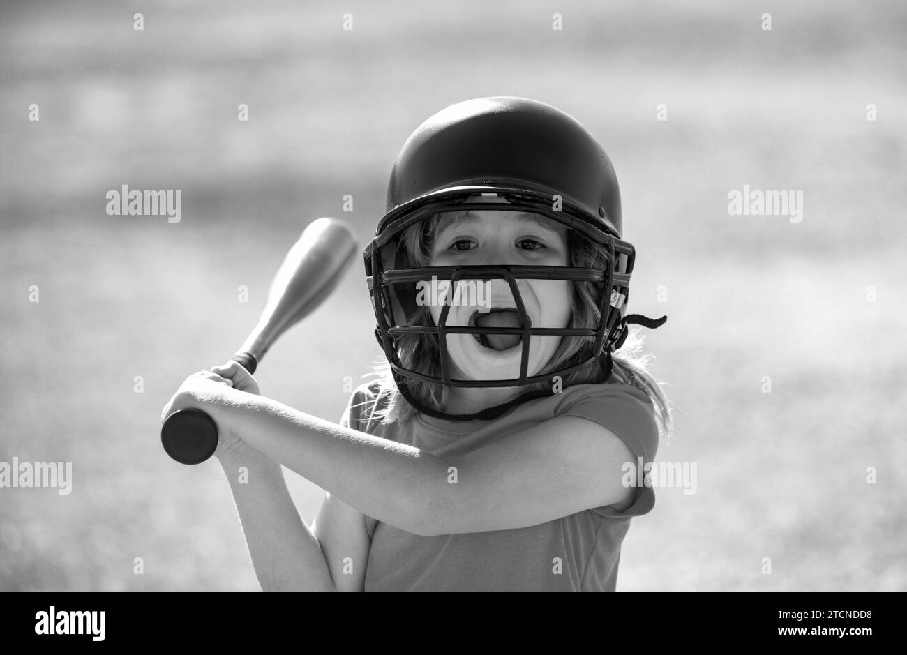 Portrait of excited amazed kid baseball player wearing helmet and hold baseball bat. Funny kids sports face. Stock Photo