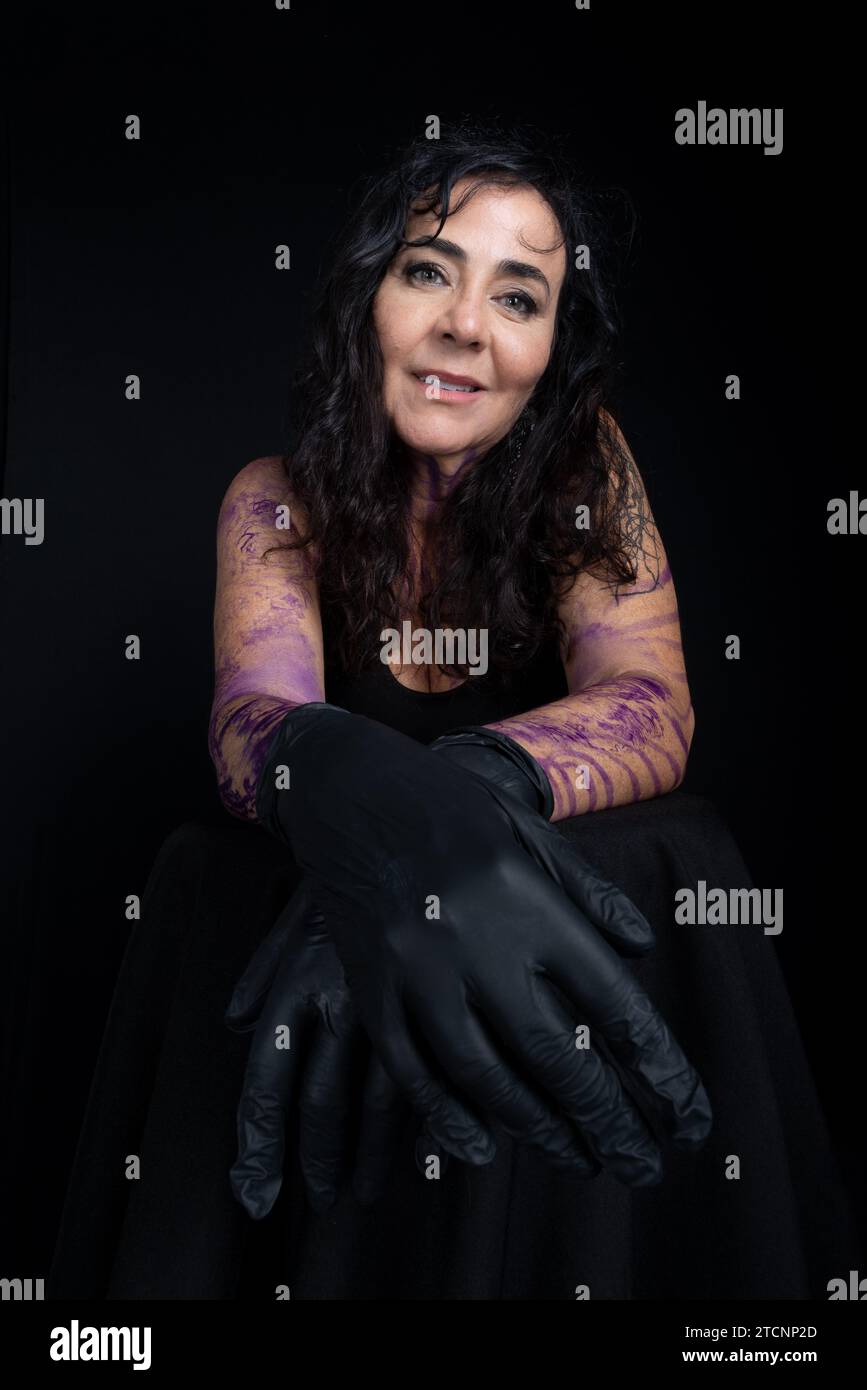Close-up of beautiful tattoo artist wearing black gloves against black background Stock Photo