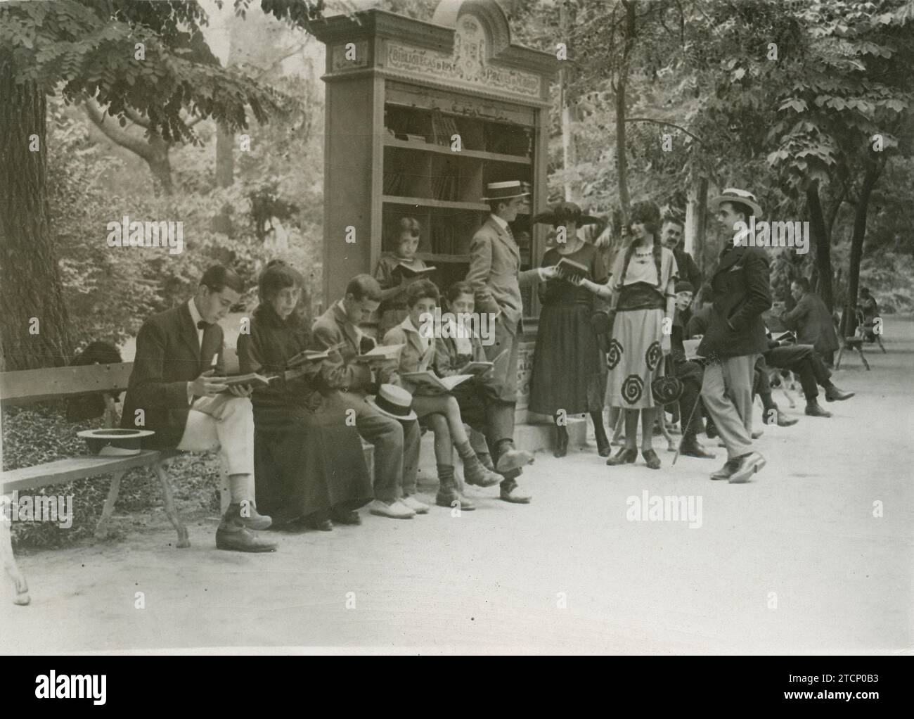 Madrid, August 1921. An image of the library established in the Retiro. Children and adults read on the benches arranged around the bookshelf full of books. In it we can read: "These books, which belong to everyone, are entrusted to the custody of everyone.". Credit: Album / Archivo ABC / Larregla Stock Photo