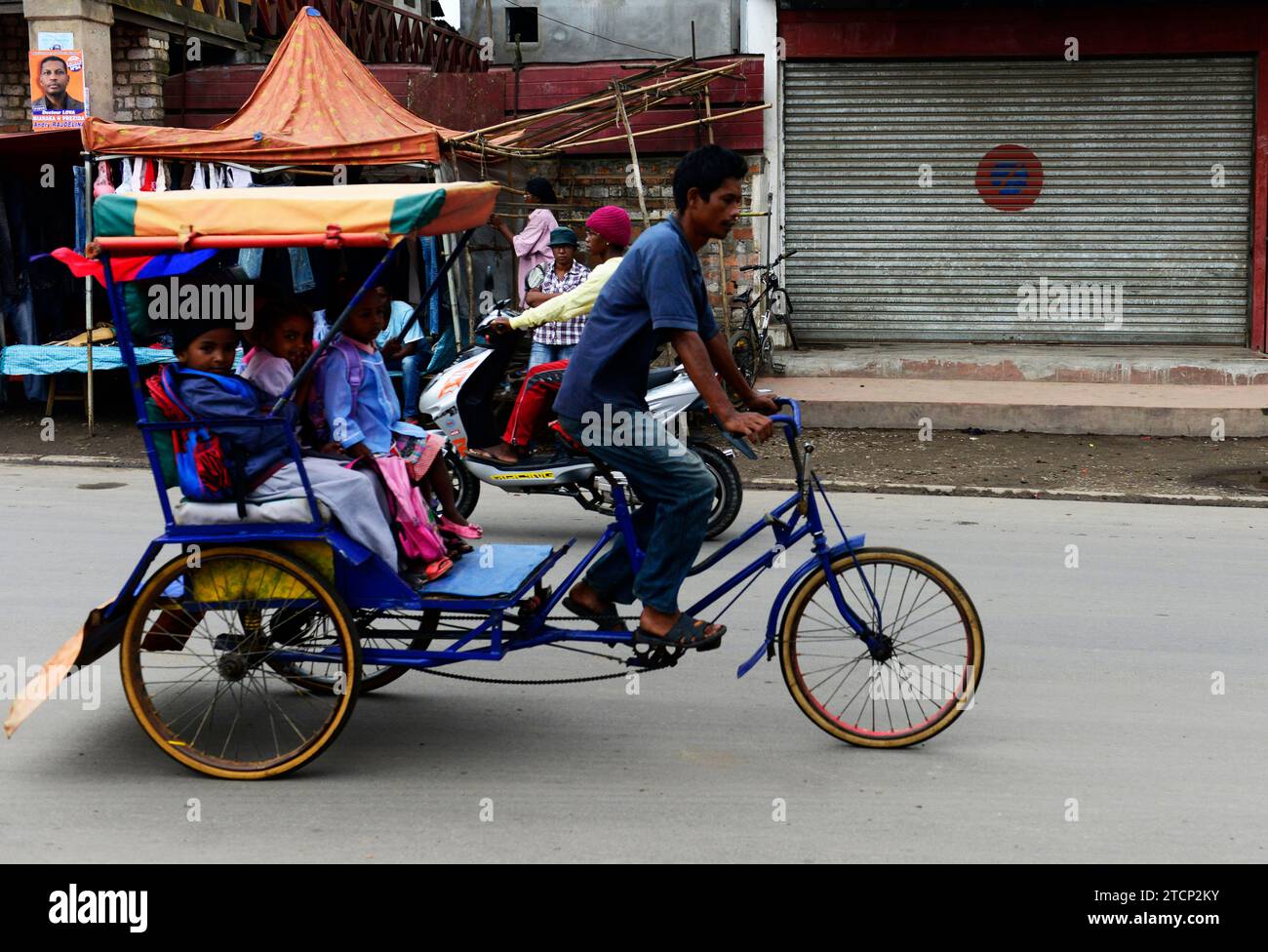 Malagasy primary school children going to school in a cycle rickshaw in Moramanga, Madagascar. Stock Photo