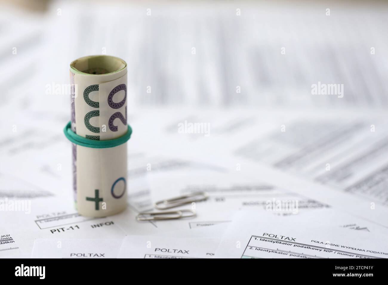 Polish zloty money PLN on big amount of polish PIT, CIT and VAT tax forms close up. Accounting