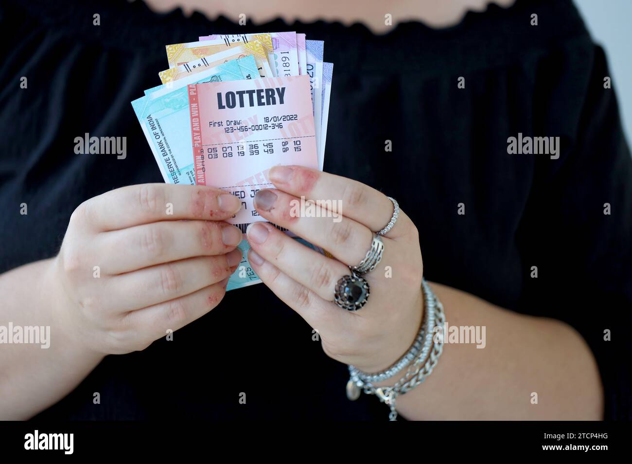 Woman hands with indian rupees bills and lottery ticket close up. Concept of gambling and