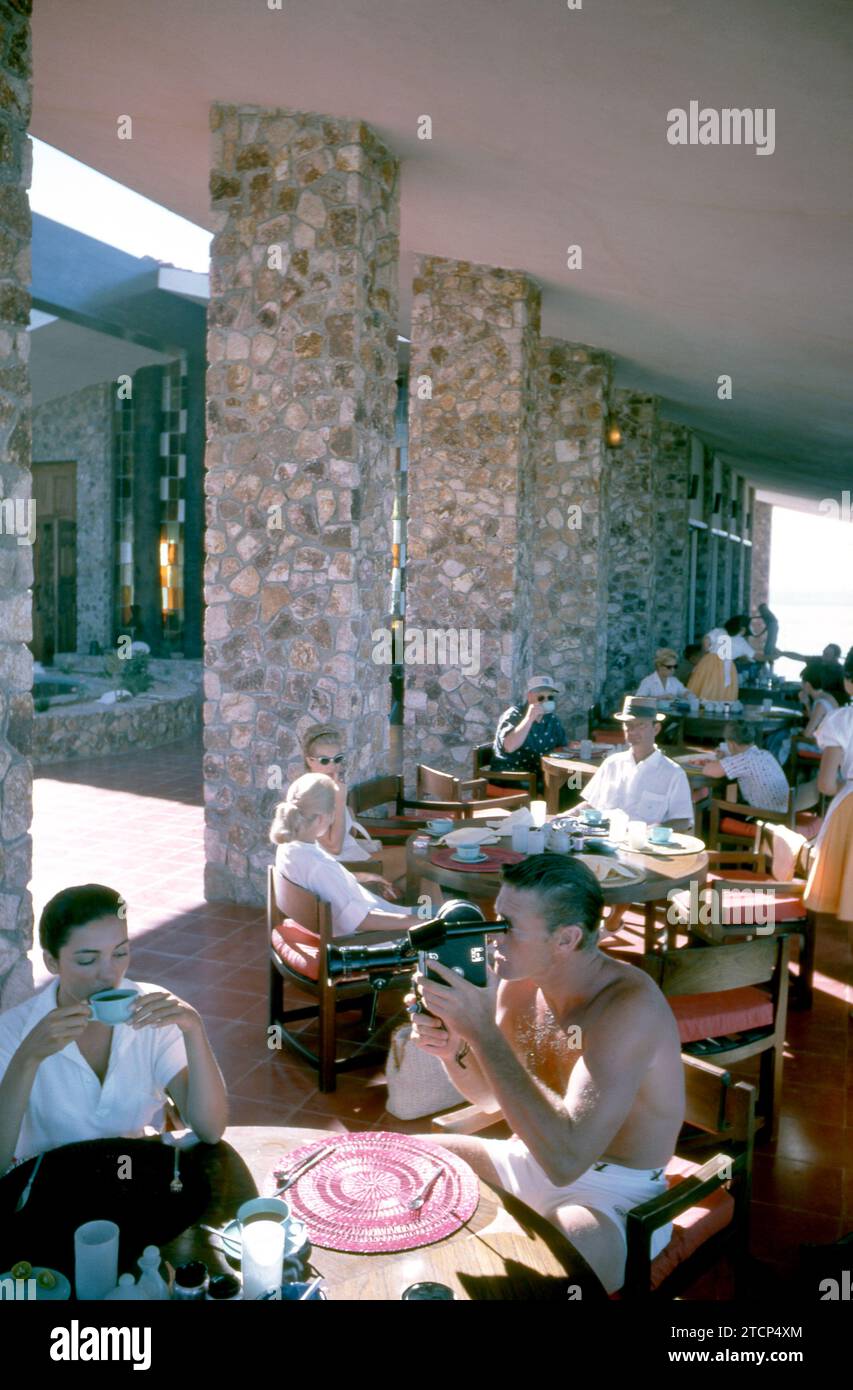 BAJA CALIFORNIA, MEXICO - JUNE, 1962:  Actor and former baseball player Chuck Connors (1921-1992) and actress fiance Kamala Devi (1934-2010) have breakfast as Connors uses a video camera at the Cabo San Lucas Hotel during a fishing trip circa June, 1962 in Baja California, Mexico.  (Photo by Hy Peskin) *** Local Caption *** Kamala Devi;Chuck Connors Stock Photo