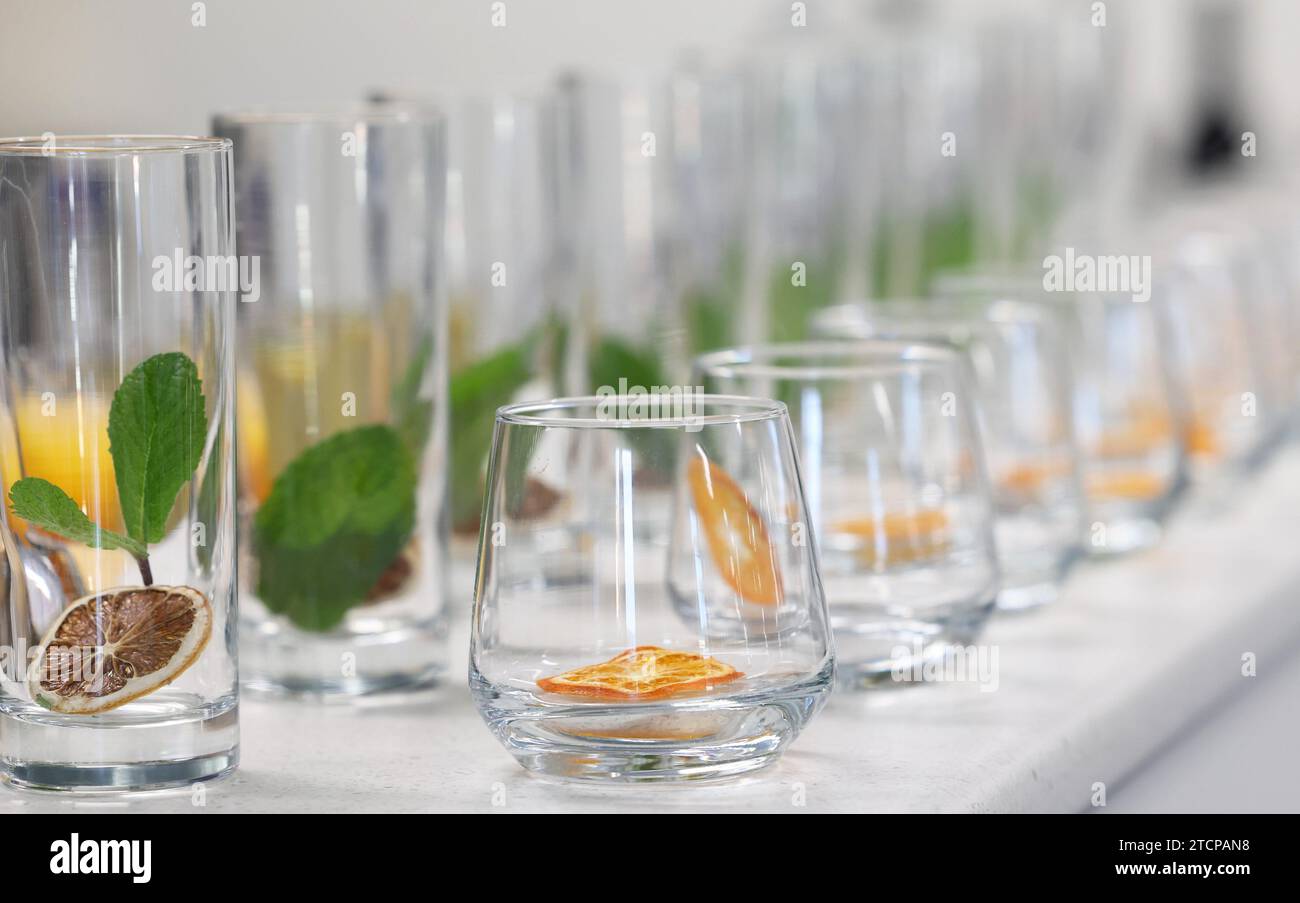 Clean glass tumblers or drinking glasses with dried dehydrated citrus fruit slices inside with mint leaves ready for a cocktail or mocktail to be pour Stock Photo