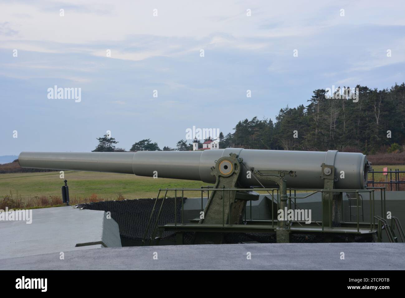 Large military canon guarding the Straight of Juan de fuca at Fort Casey with Admiralty Head Lighthouse. Stock Photo
