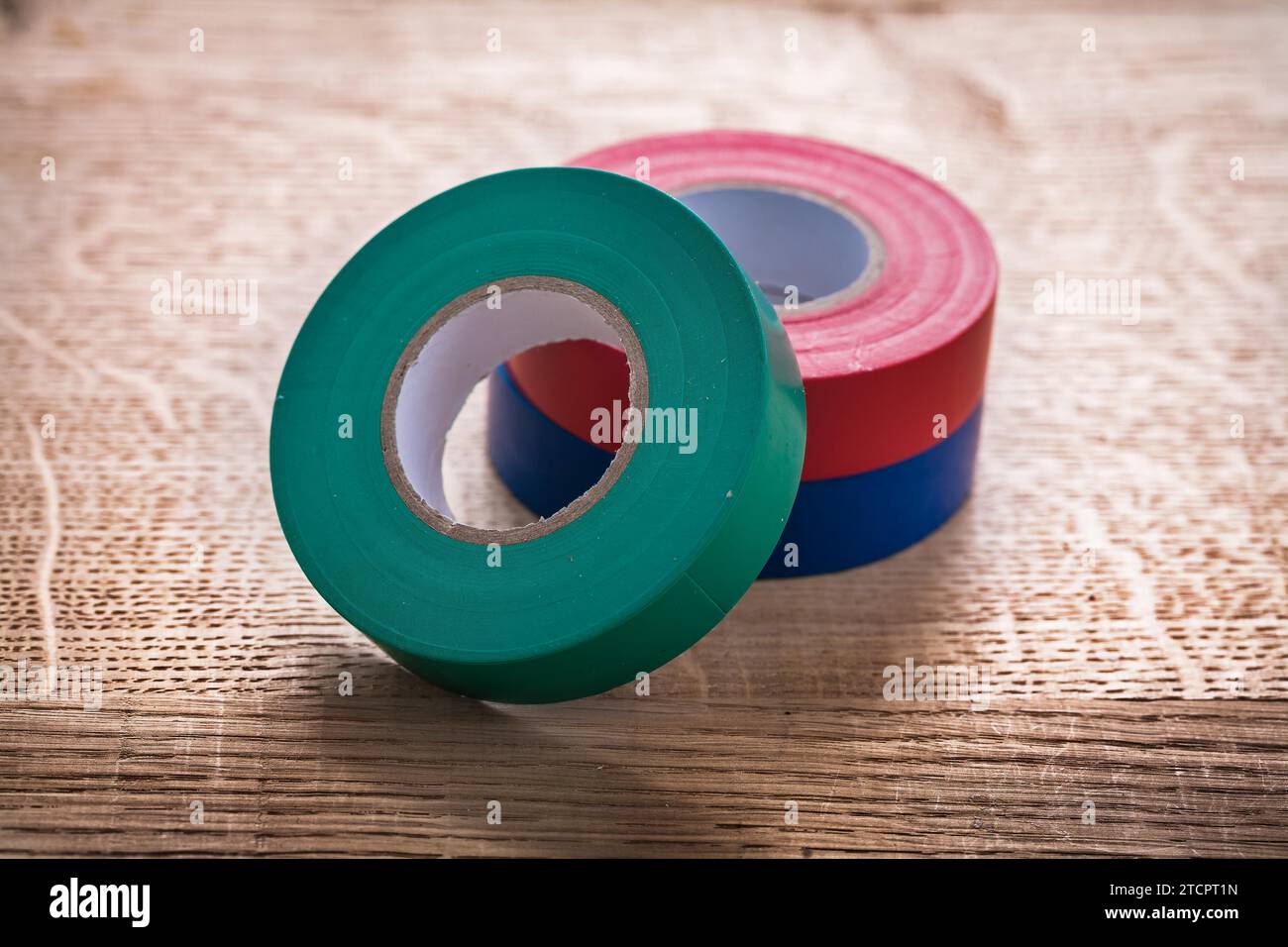 Green red blue Rolls of insulating tape on wooden panel Construction concept Stock Photo