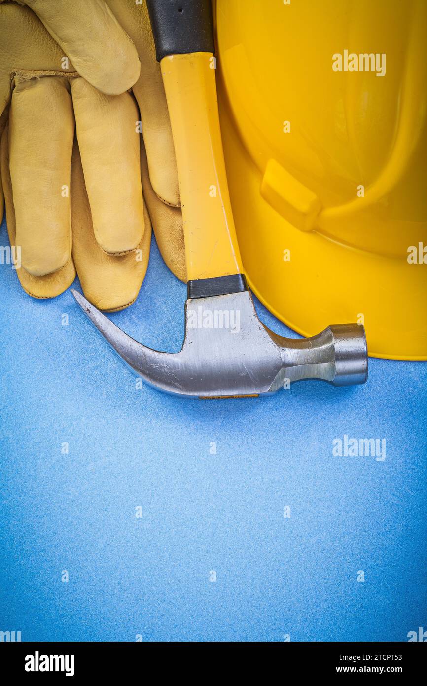 Assortment of claw hammer safety gloves hard hat on blue background