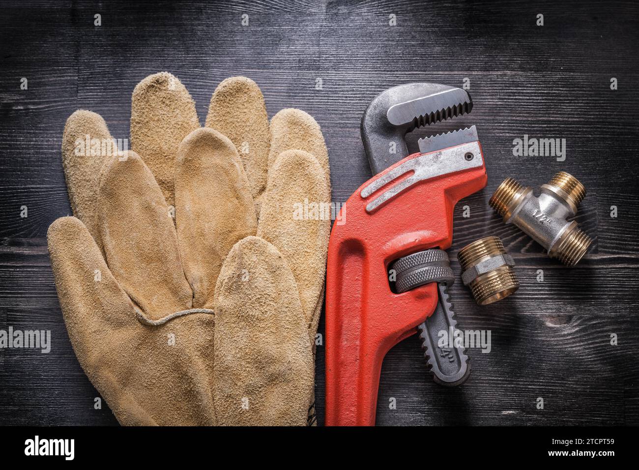 Adjustable spanner Sanitary fittings Leather protective gloves on wooden board Stock Photo