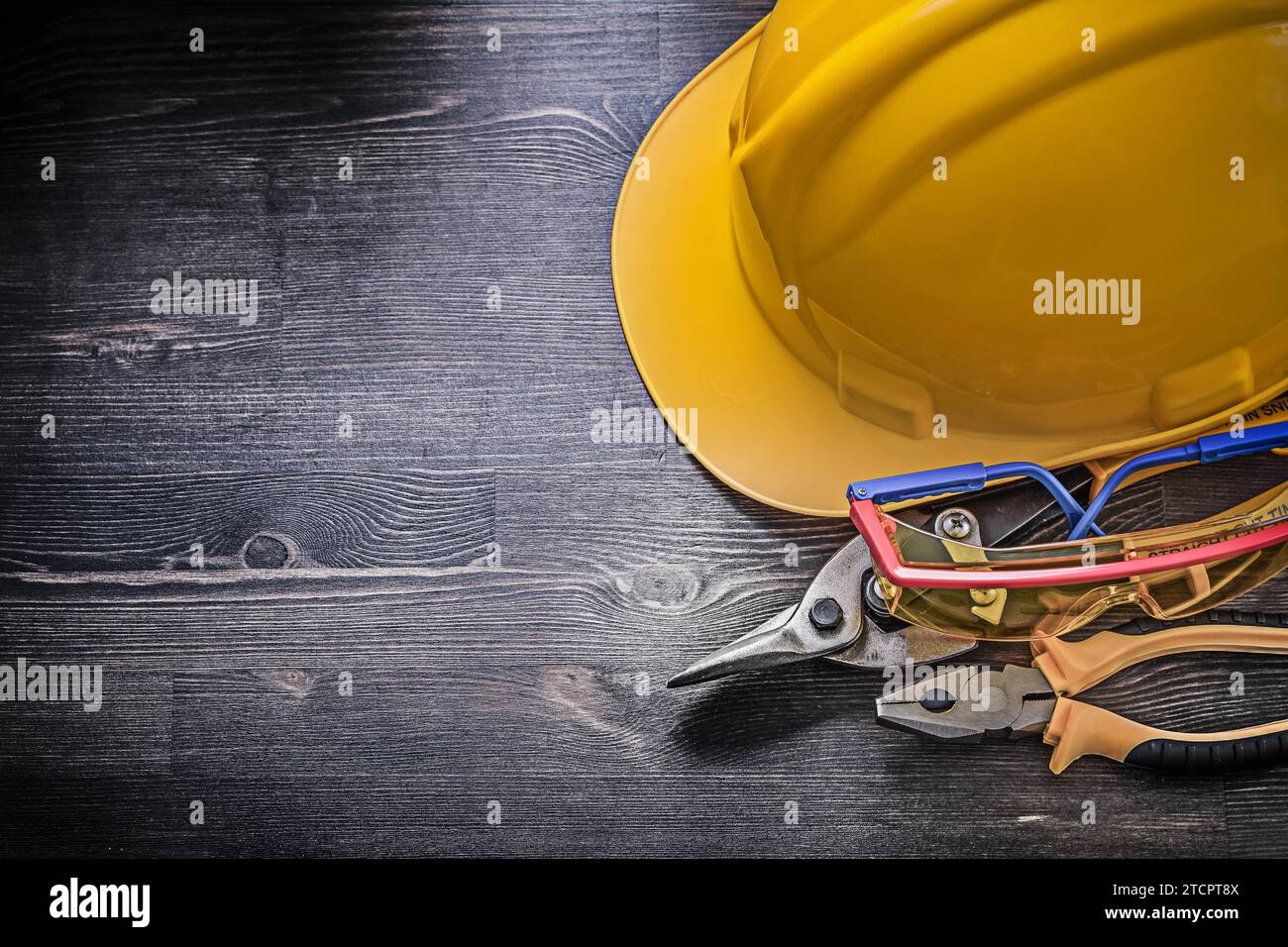 Construction helmet Safety goggles Pliers Tin snips on a wooden background Stock Photo