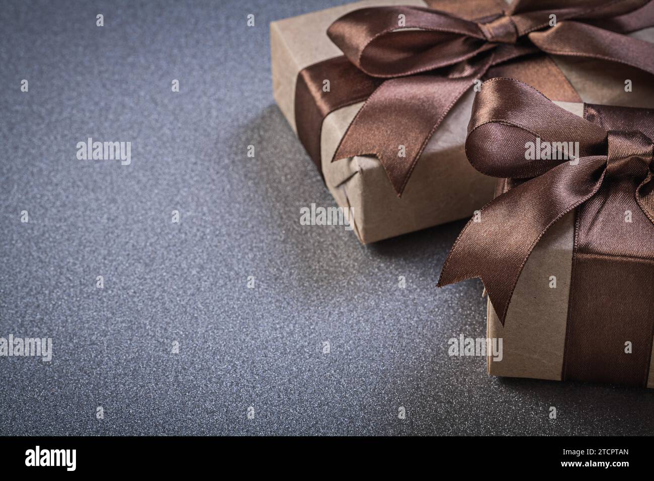 Boxed gifts in brown wrapping paper on grey background Celebration