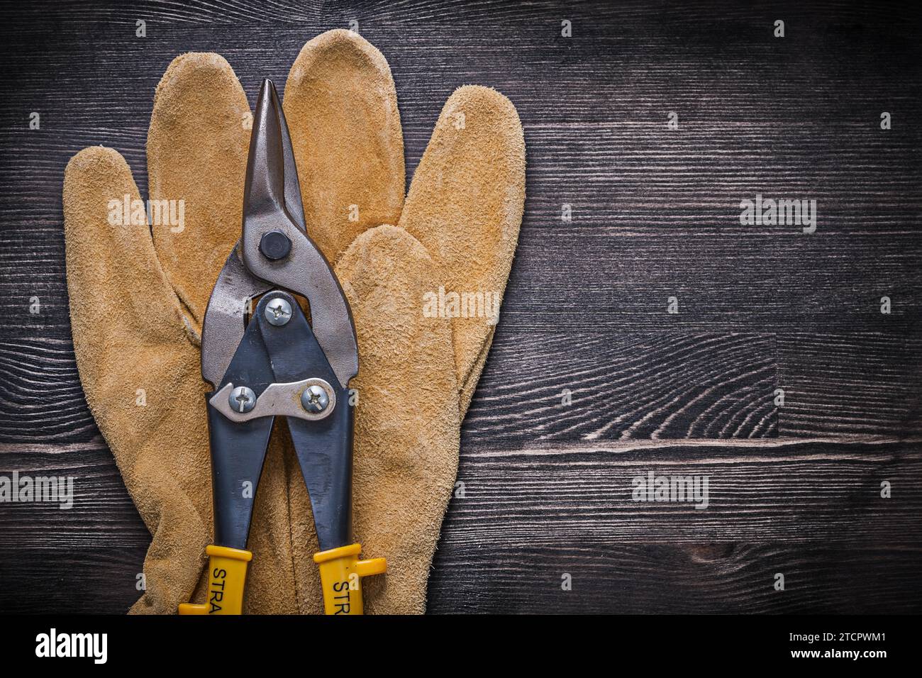Leather protective glove Wire cutter on wooden board Construction