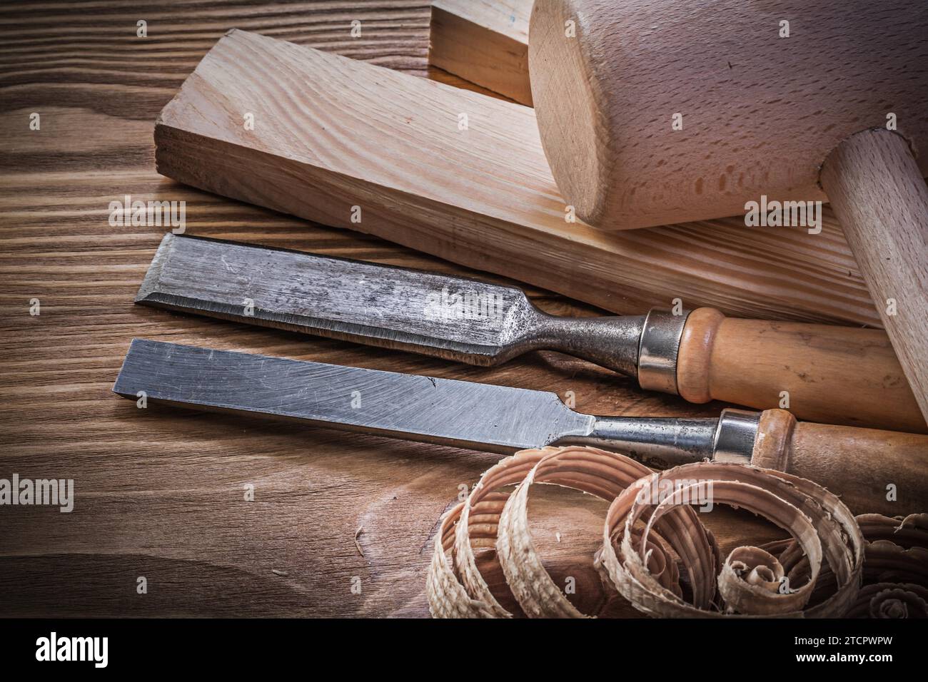 Lump hammer wooden bolt firmer chisel planning chips on vintage wooden board Stock Photo