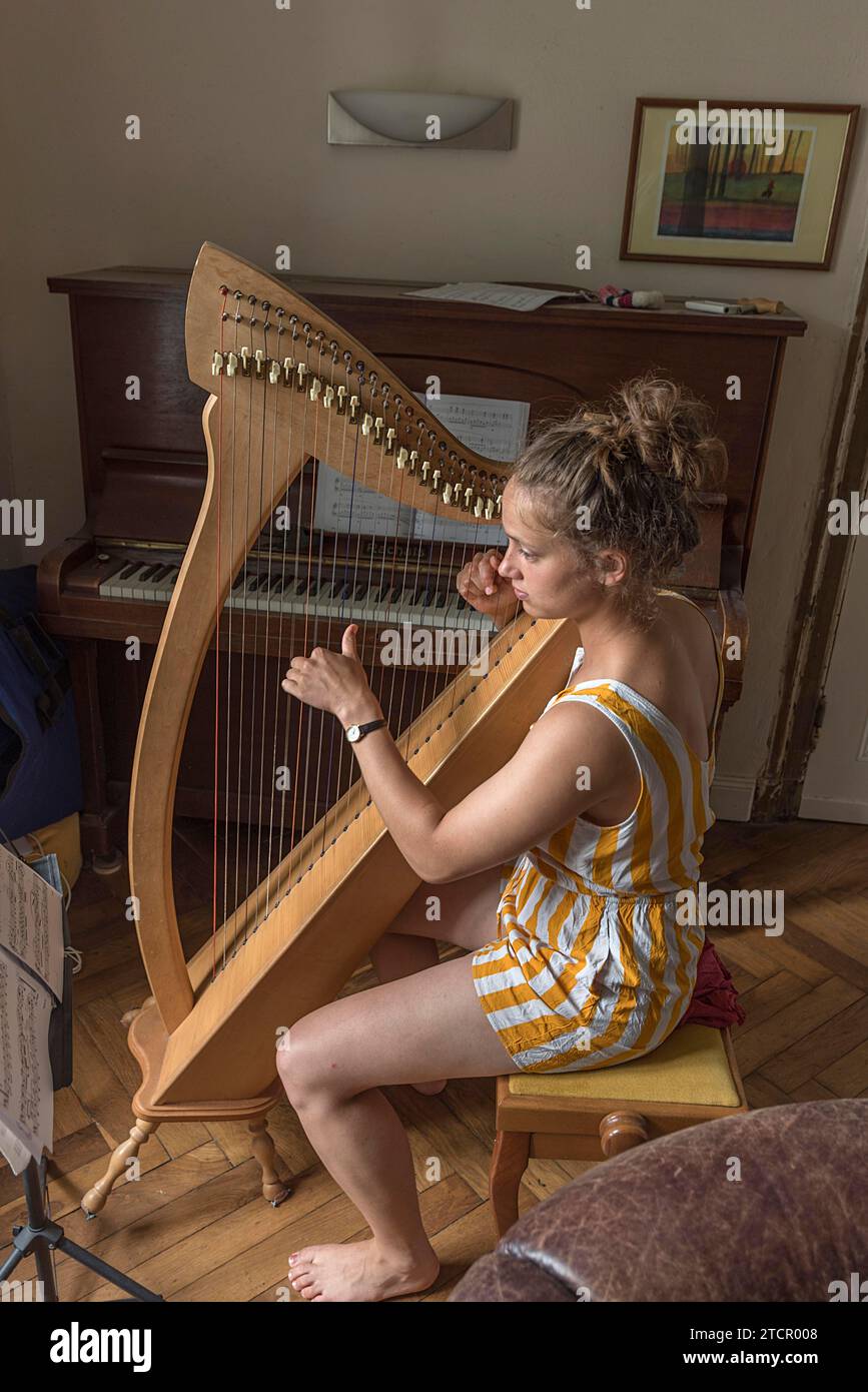 Young woman playing the harp at home, Mecklenburg-Vorpommern, Germany Stock Photo