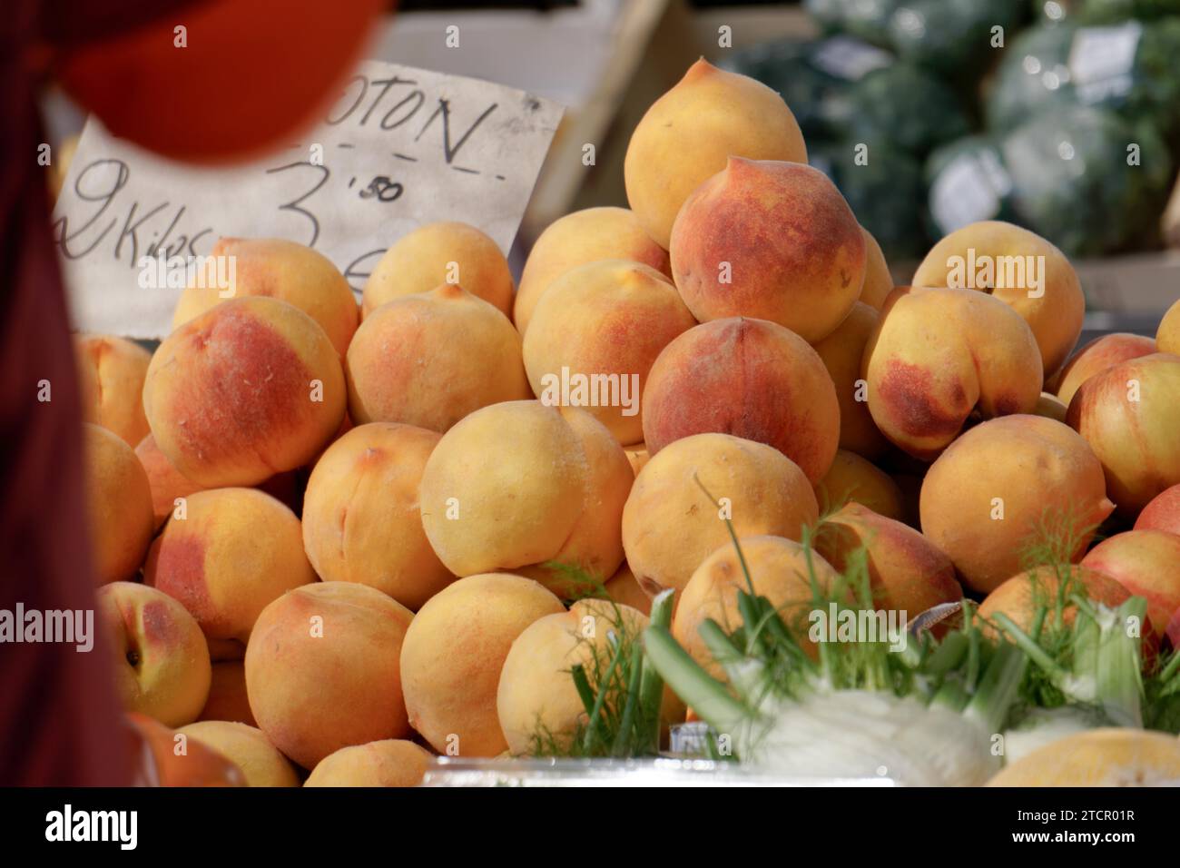 Pile of peaches on a table in a street market with a price sign Stock