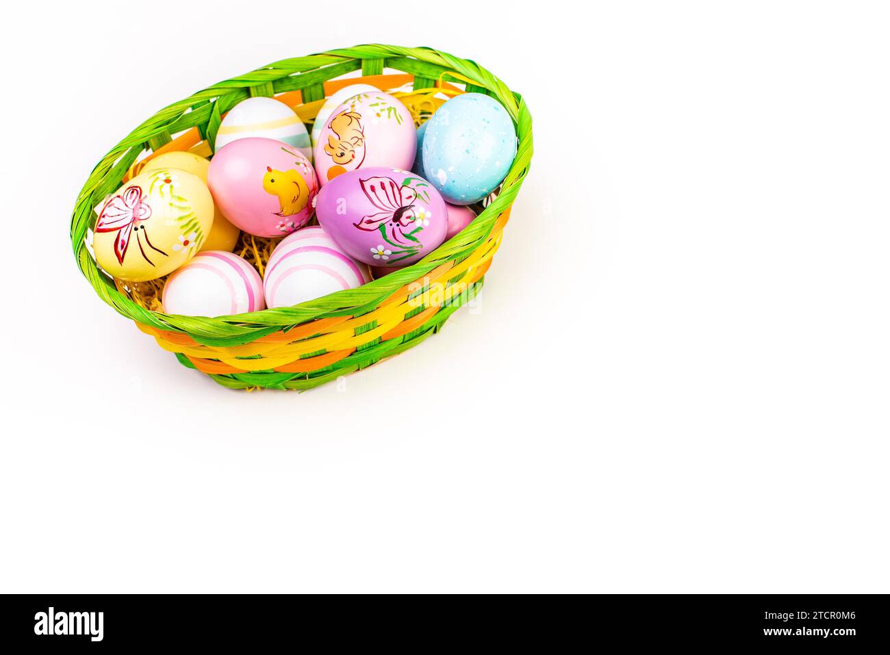 Wicker basket with Easter eggs hand painted on white background. Copy ...