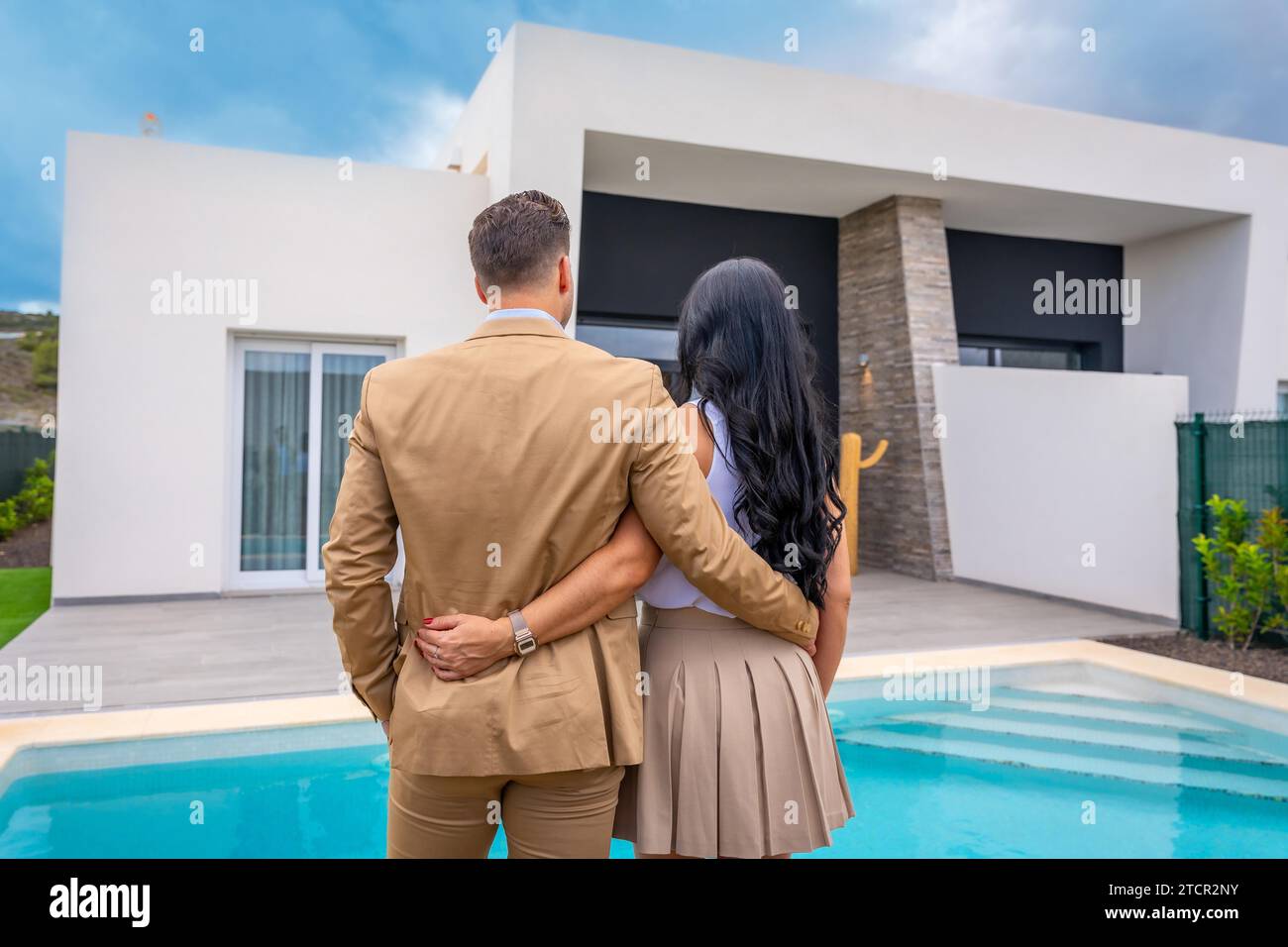 Rear view of a couple facing their new luxury home from the pool Stock Photo