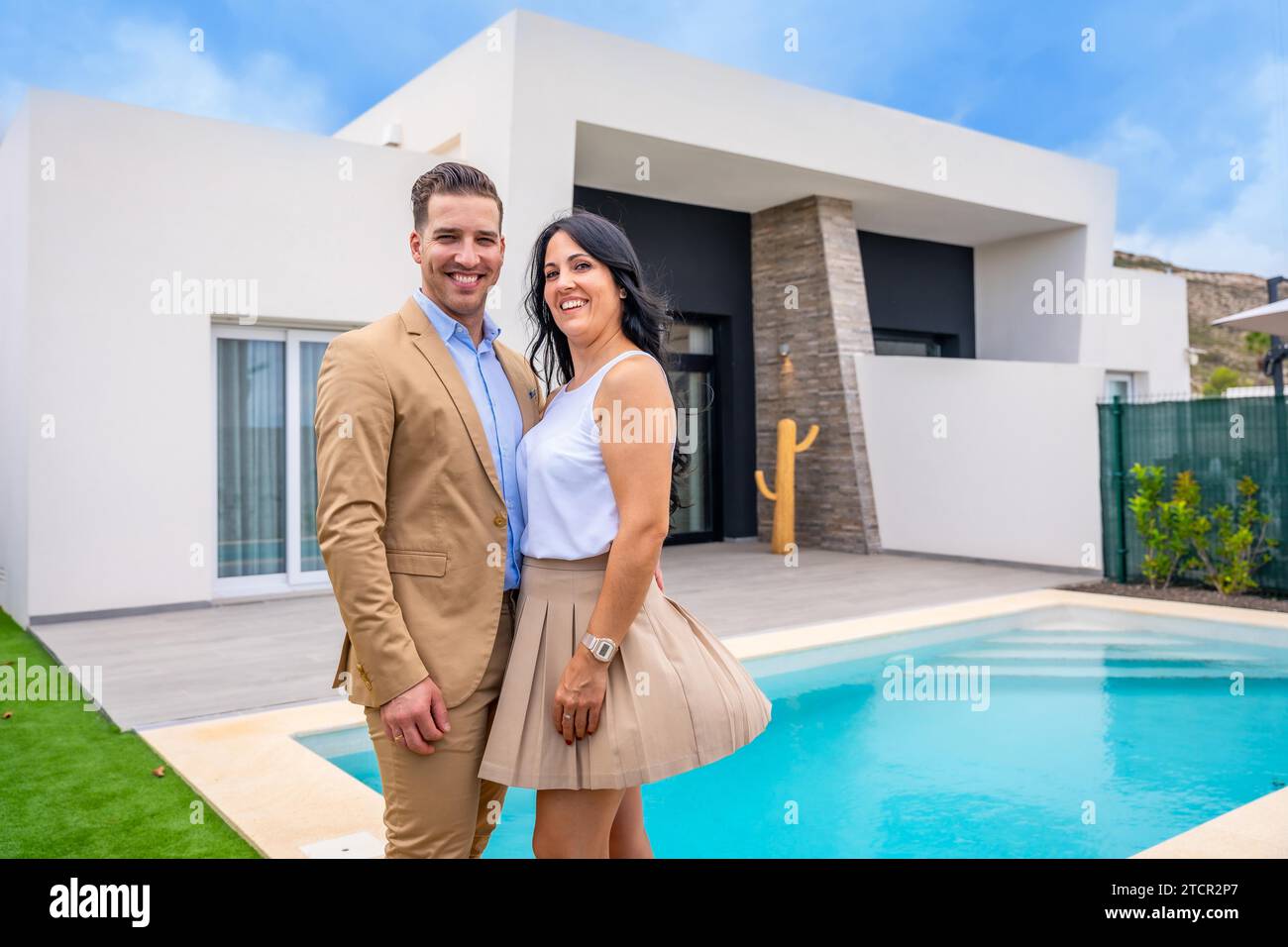 Portrait of a happy couple standing on the pool of their new luxury home Stock Photo