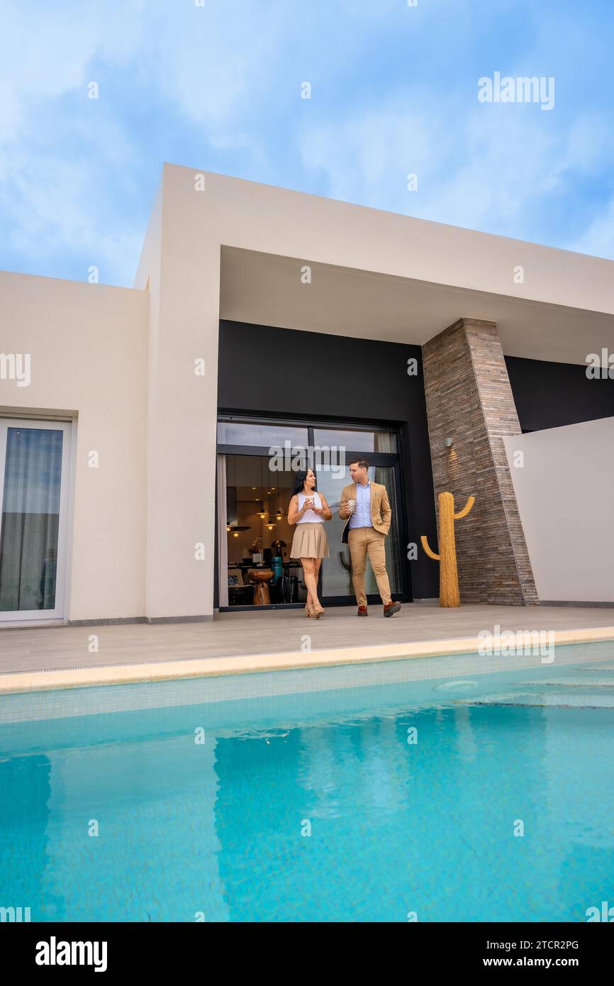 Vertical photo of a couple next to the pool of their new luxury residence Stock Photo