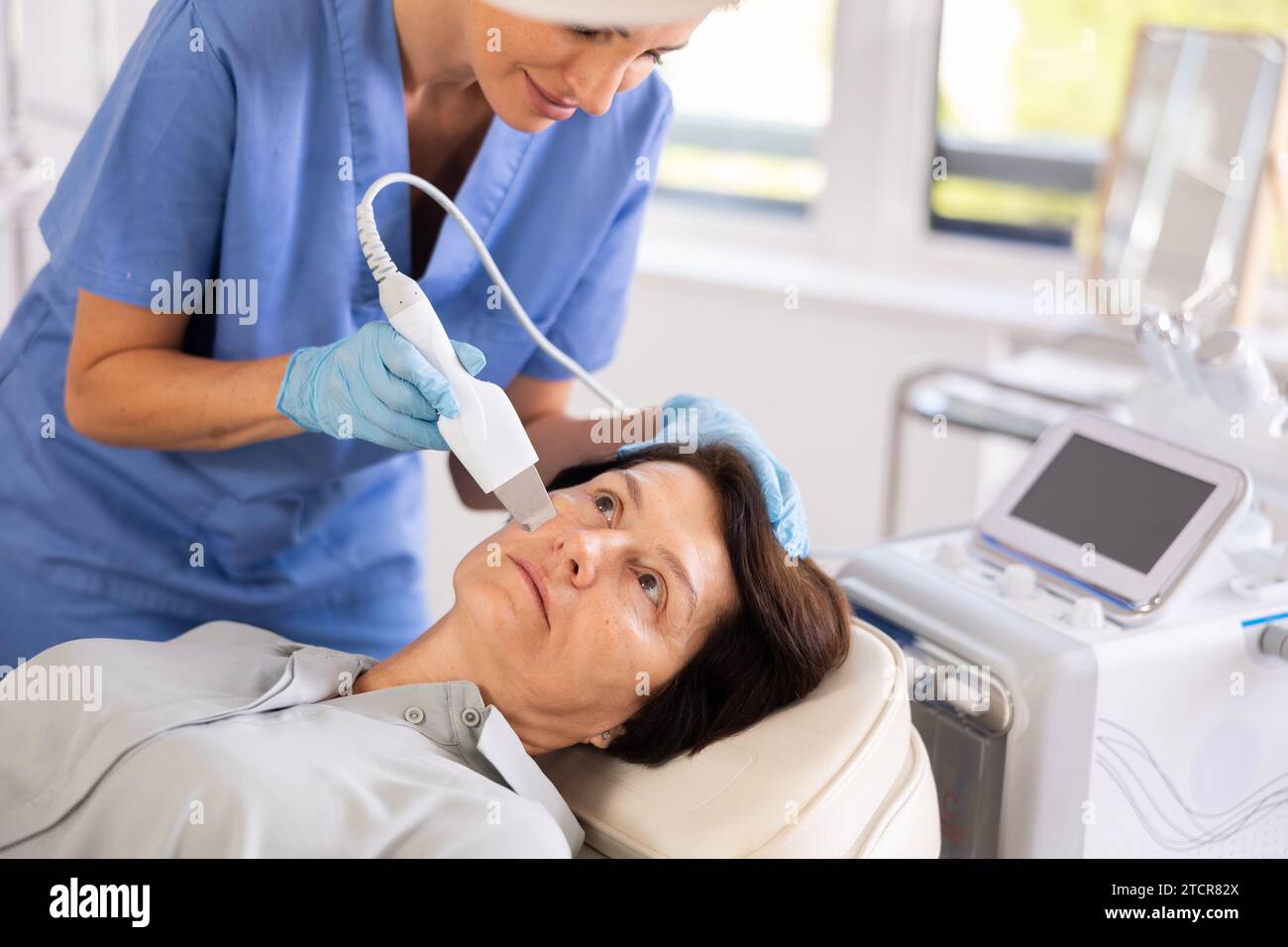 Elderly female patient receiving facial skin cleansing with ultrasonic ...