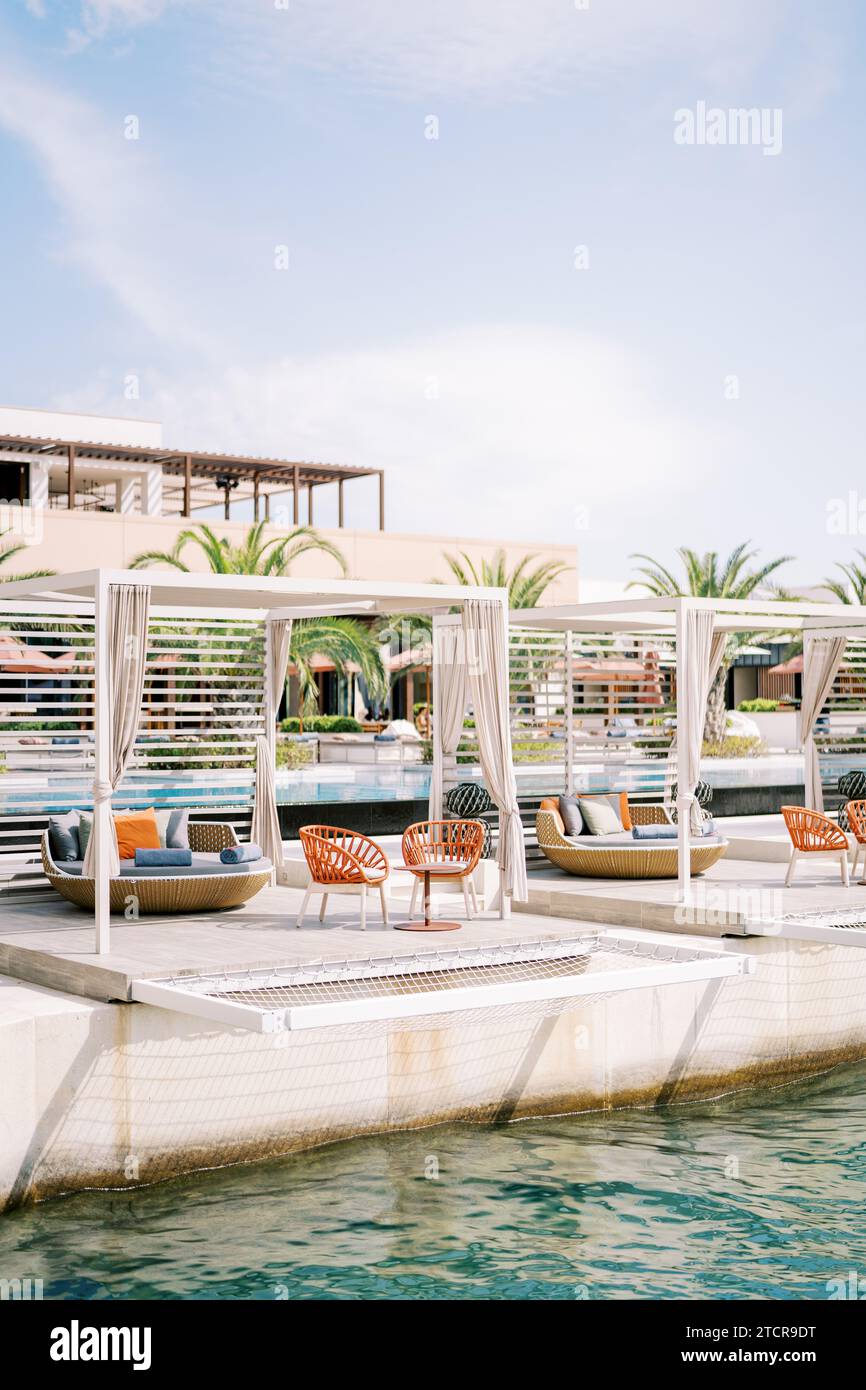 Wooden gazebos with armchairs and sofas on the pier by the sea. One and Only, Portonovi, Montenegro Stock Photo