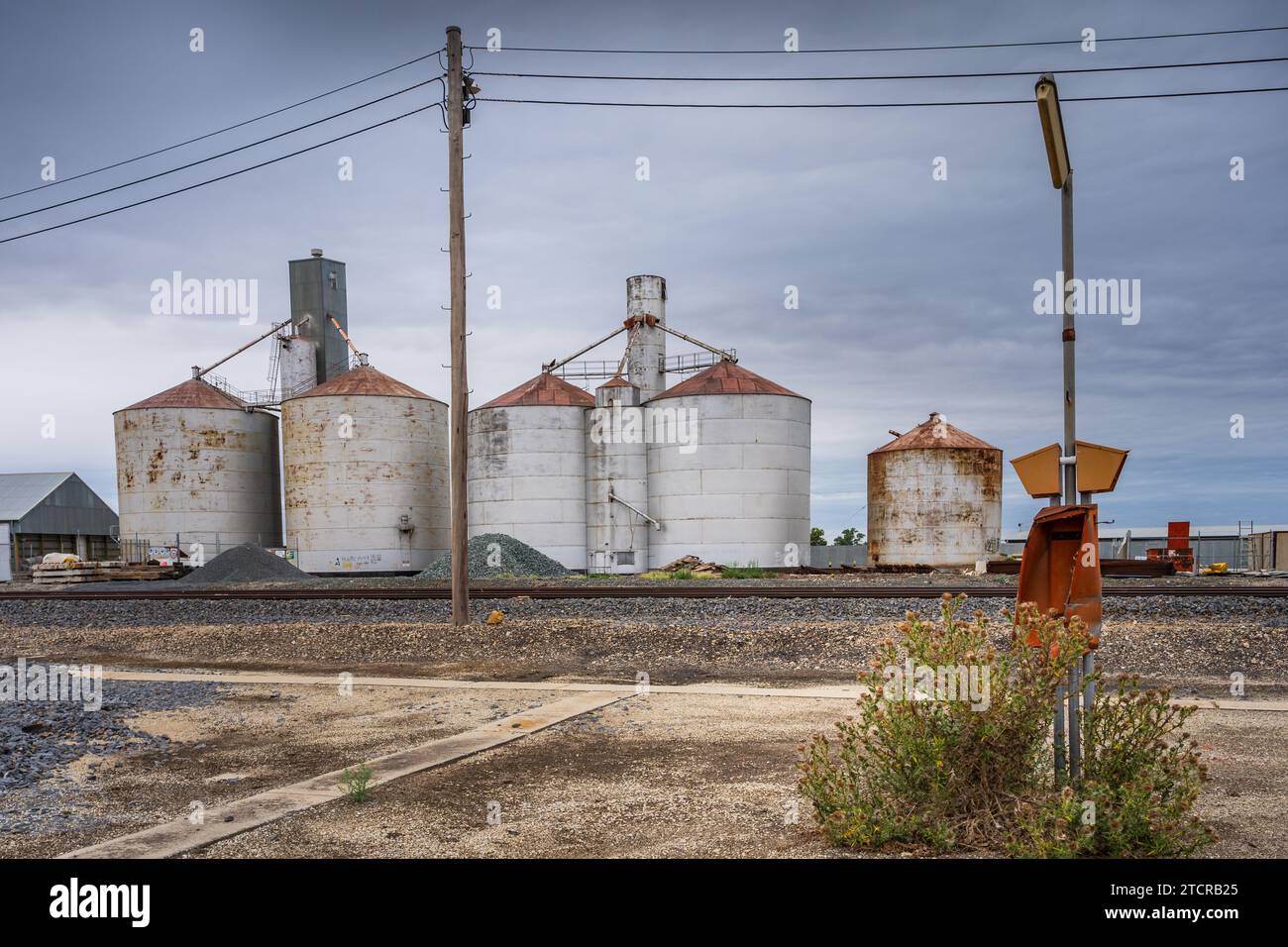 An abandoned caravan park alongside a railway line next to large grain