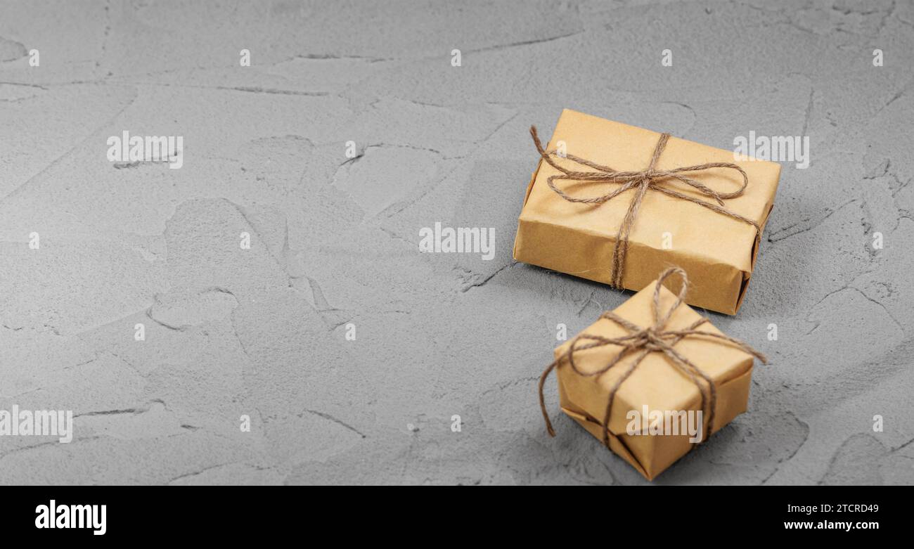Christmas gift boxes on neutral gray table background. Congratulation postcard, present tag mockup, minimalist style Stock Photo