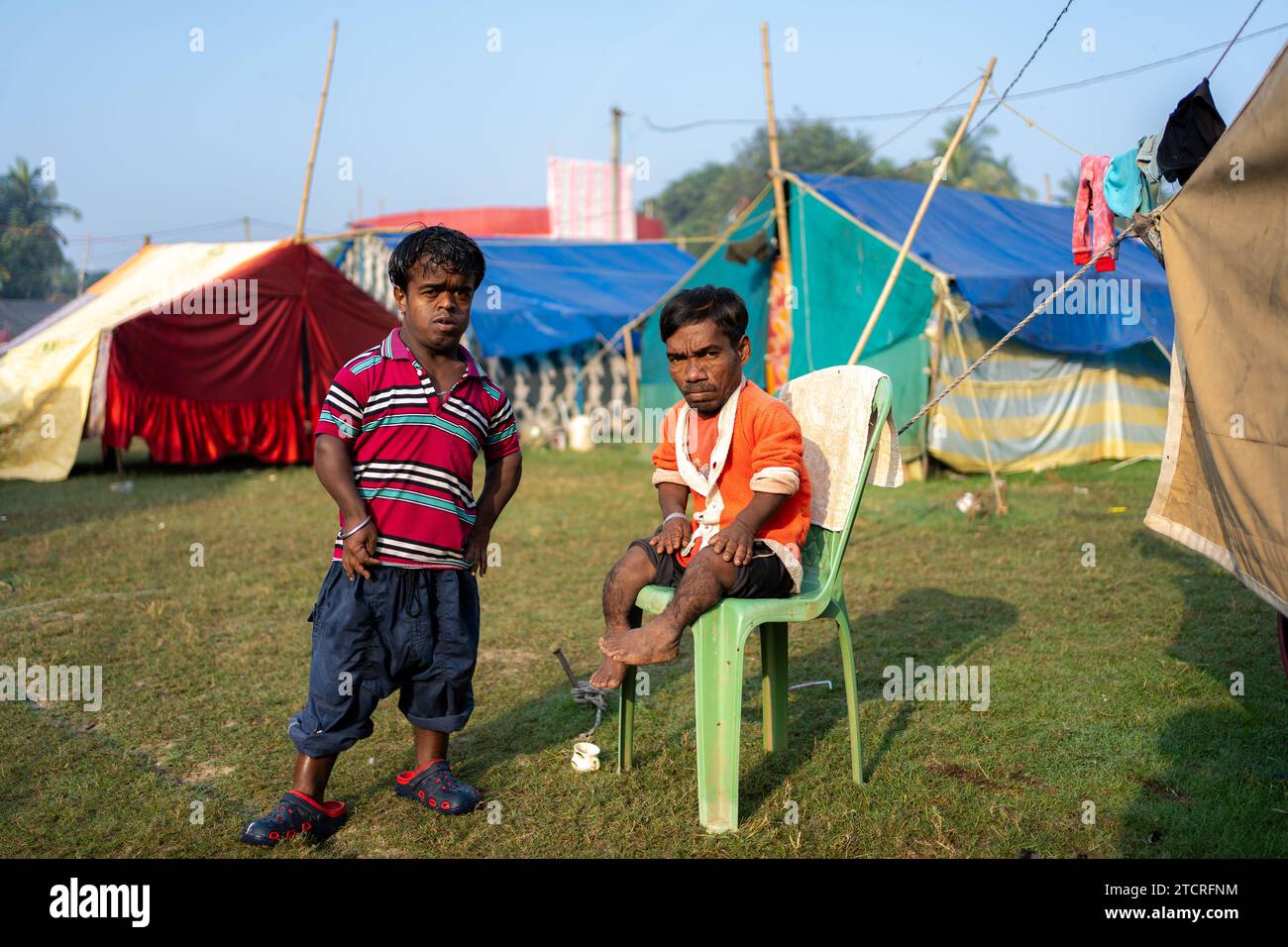 Two dwarf men, who play the role of joker in a circus, are seen in front of their tents in a ground where they live during winter season. Winter and childhood meant a time when there was a distinct attraction and love for the circus. But now the times have changed so the demand has also decreased especially after the show of any kind of animals in the circus has stopped, the owners of the circus teams are more upset. Now the game is shown only with jokers or people. And as a result the income has decreased. Now even the little ones have lost interest in the circus. As a result, the income of t Stock Photo